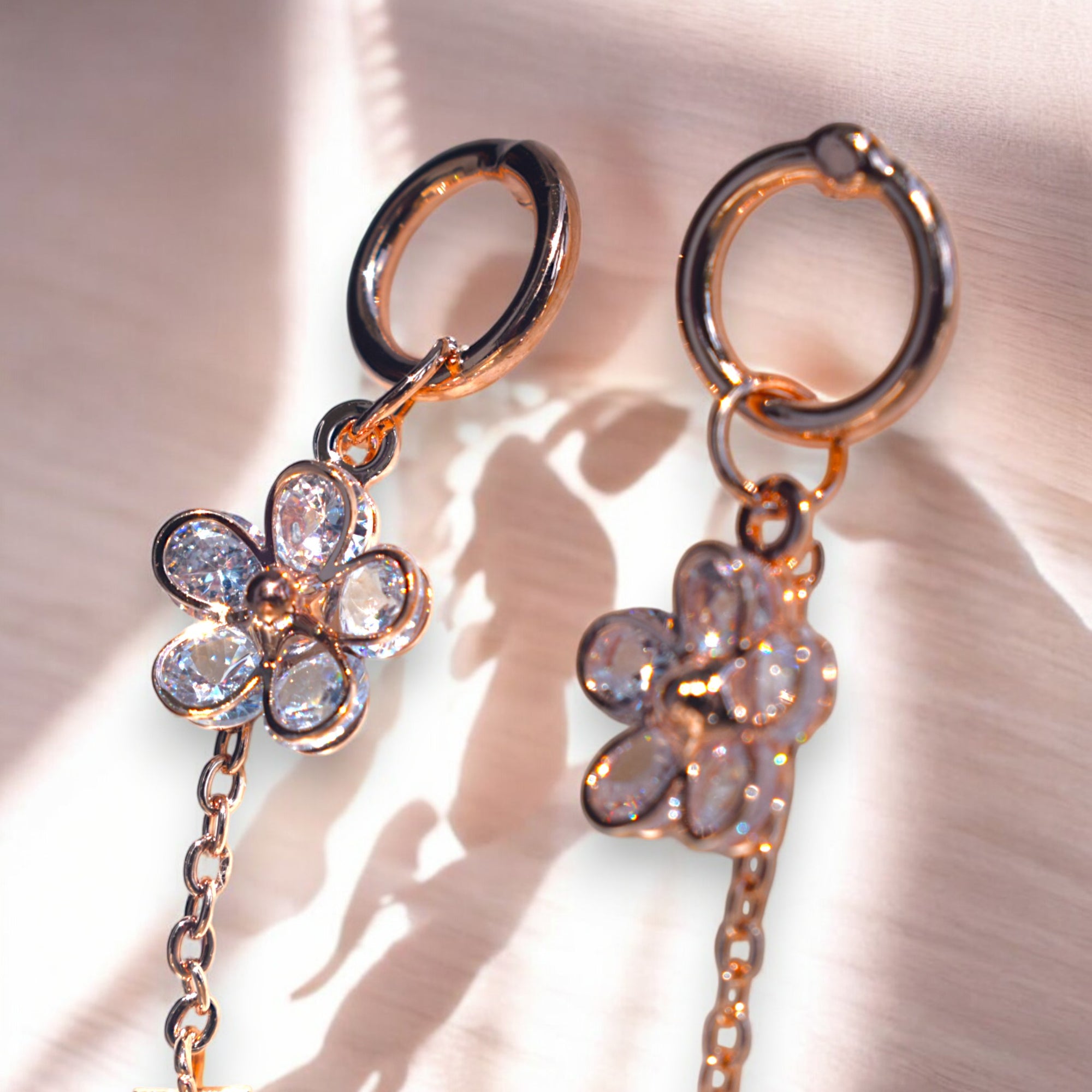 close up of a rose gold flower drip zirconia stone earrings on a white marble floor background