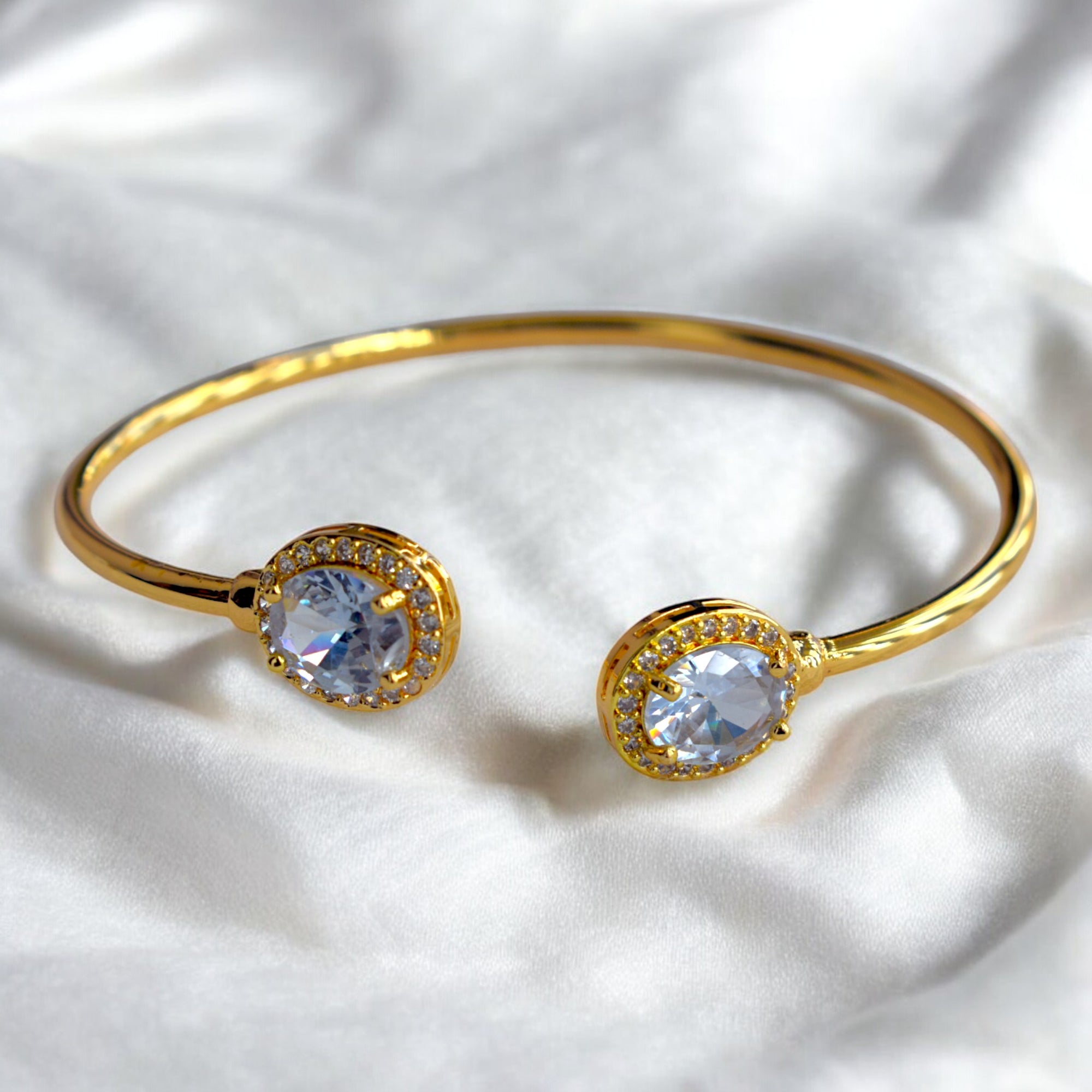 a diamond studded gold bangle placed on a white satin cloth