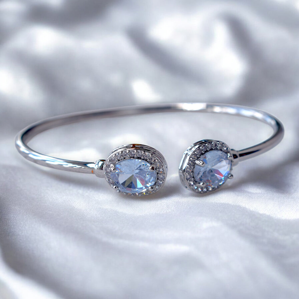 a diamond studded silver bangle placed on a white satin cloth