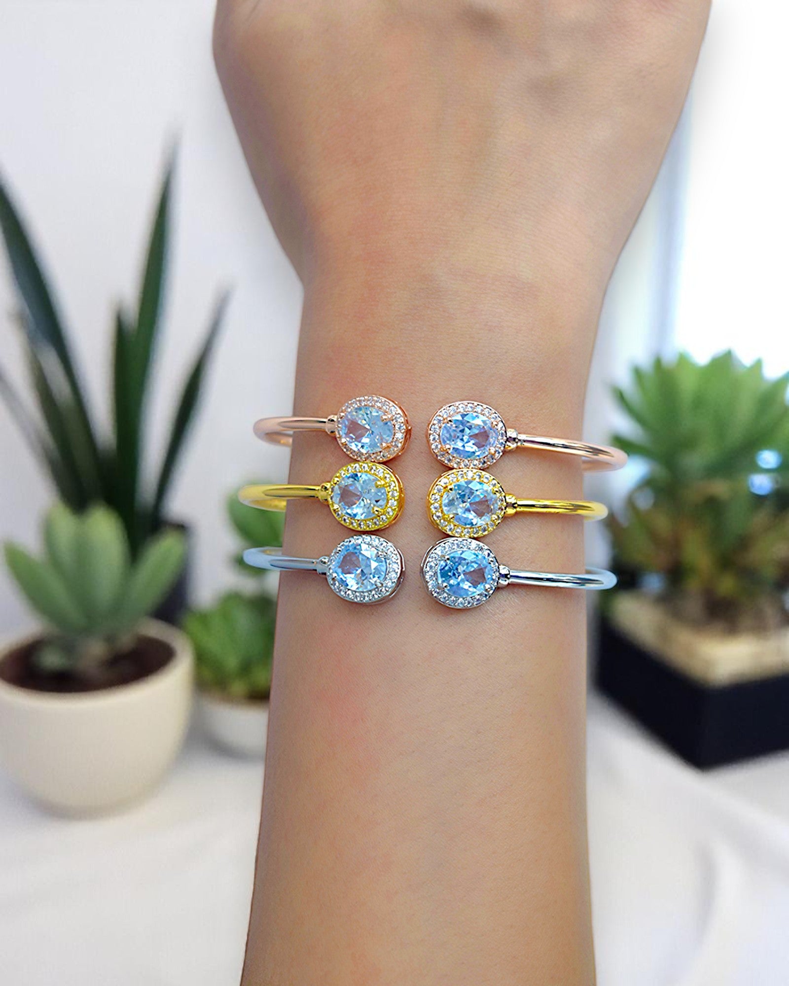 a girl wearing a three diamond studded bangles on her right hand with plants in the background