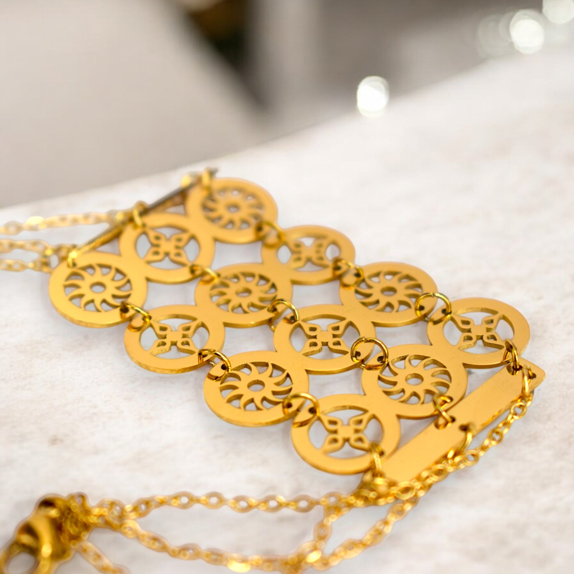 close up of a gold color circle design bracelet on a white satin cloth