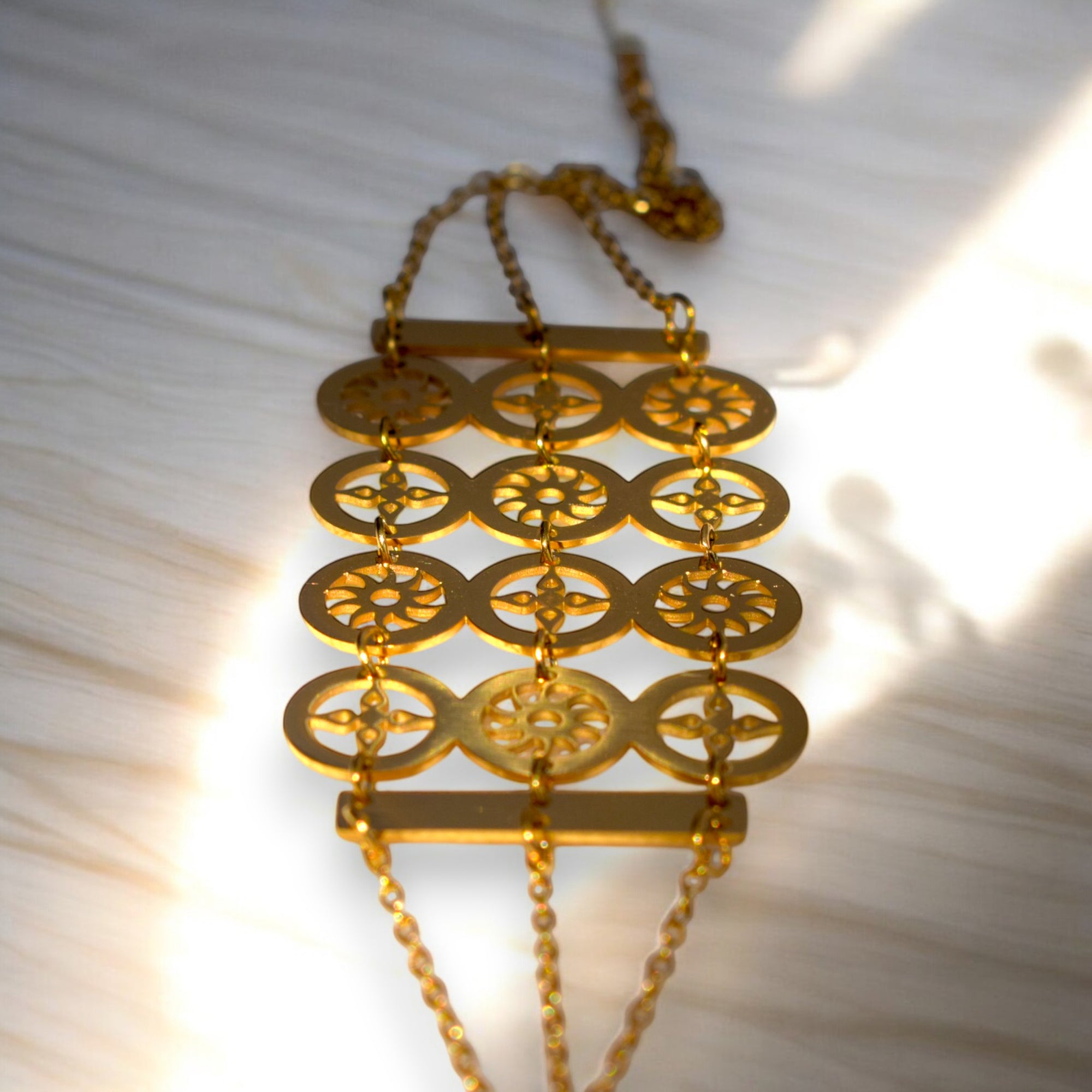close up of gold color circle design bracelet on a white satin cloth and the sun rays shining on it