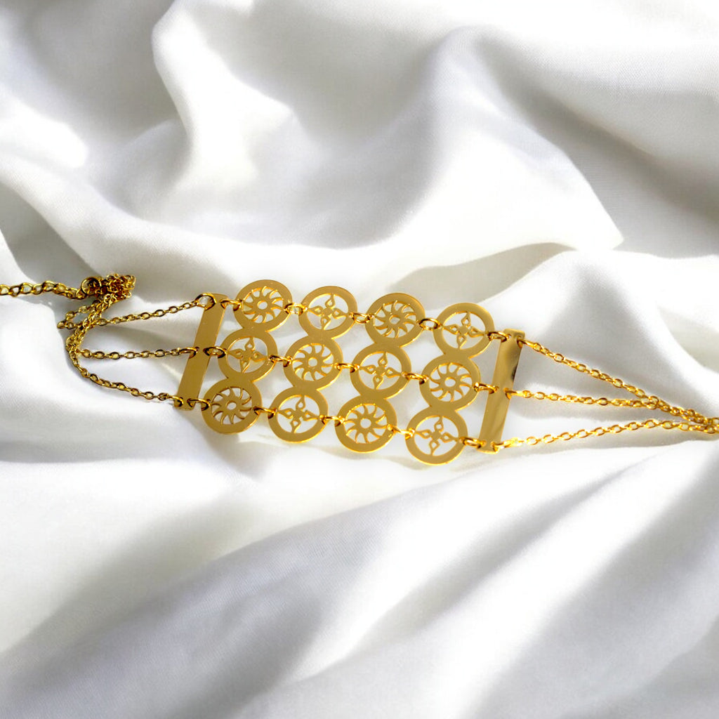 gold color circle design bracelet on a white satin cloth