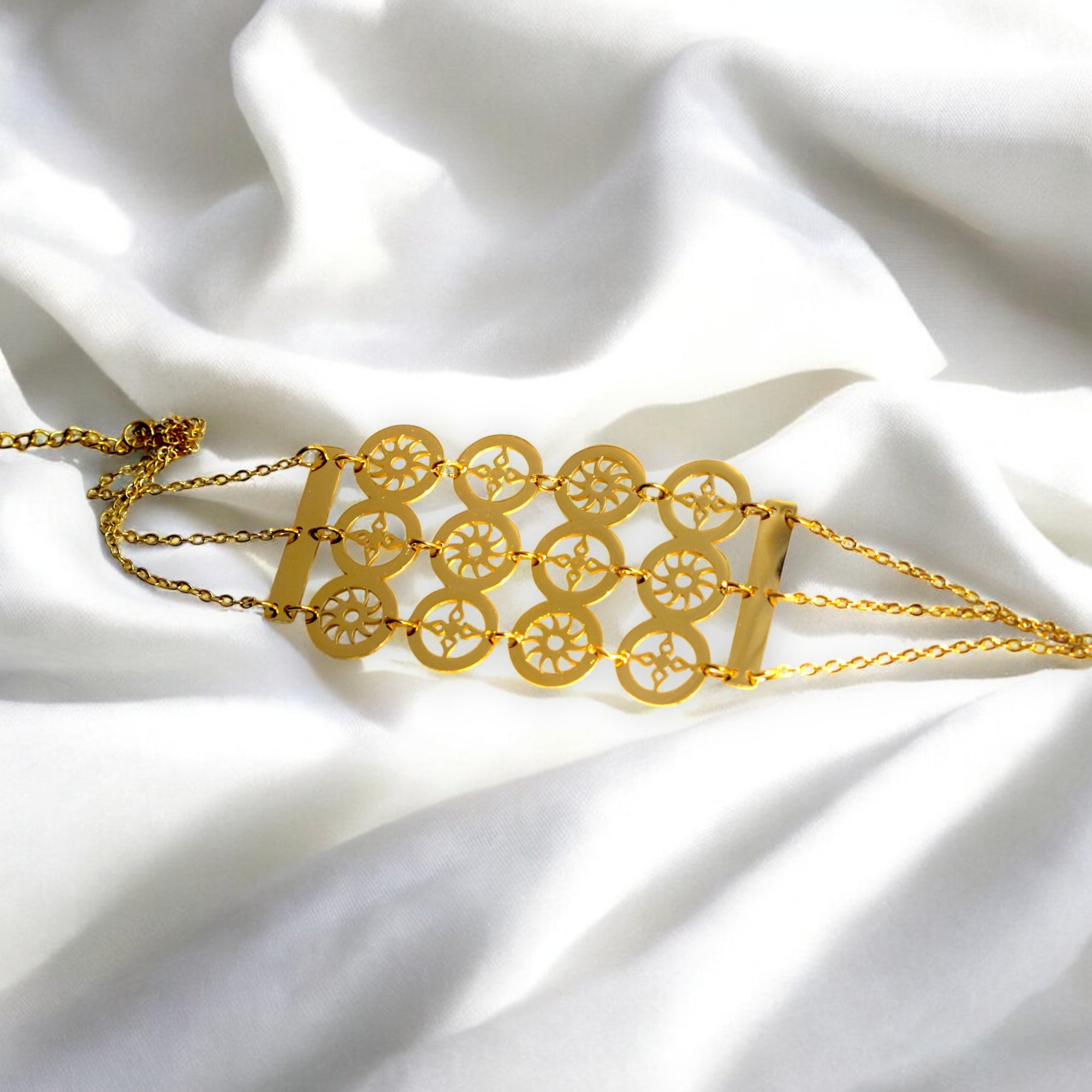 gold color circle design bracelet on a white satin cloth