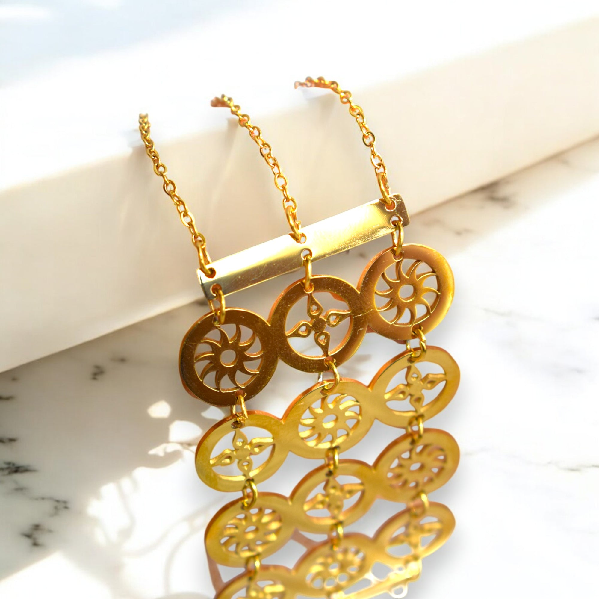 close up gold color circle design bracelet on a white marble floor