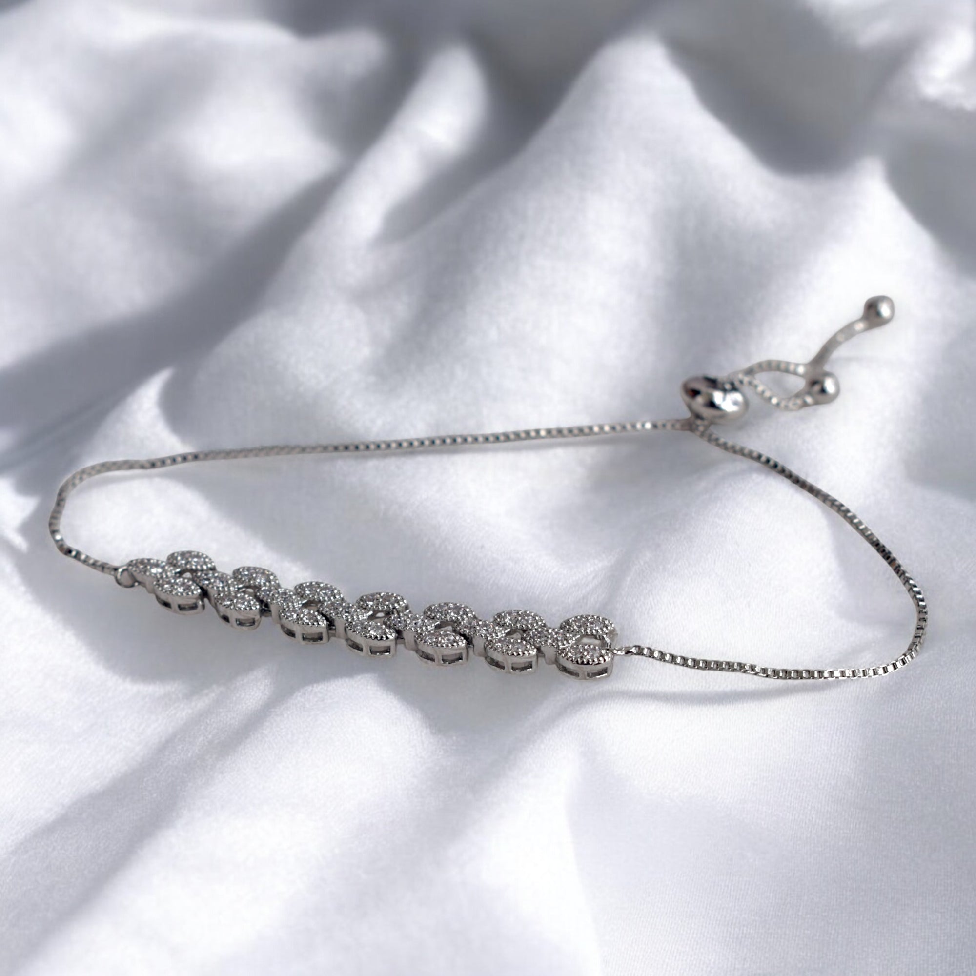 silver diamond studded bracelet on a white satin cloth