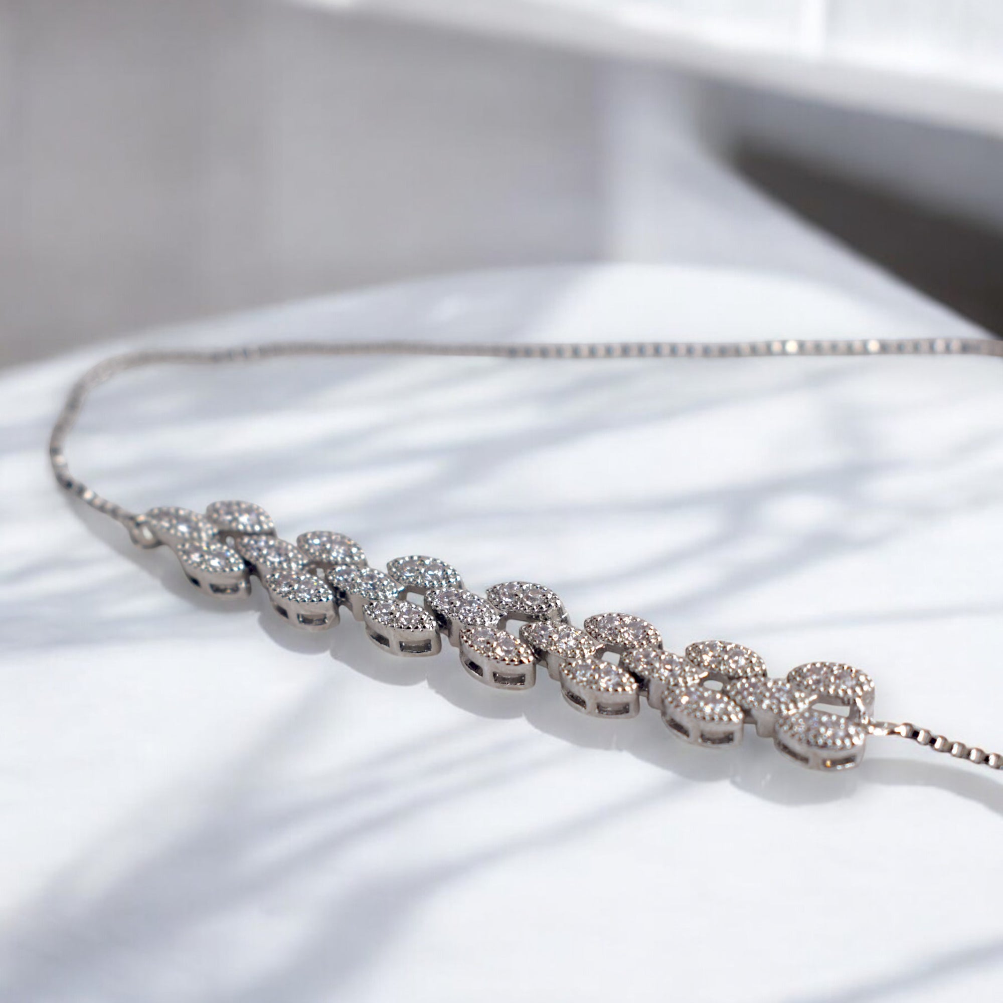 white diamond studded silver bracelet on a white marble floor
