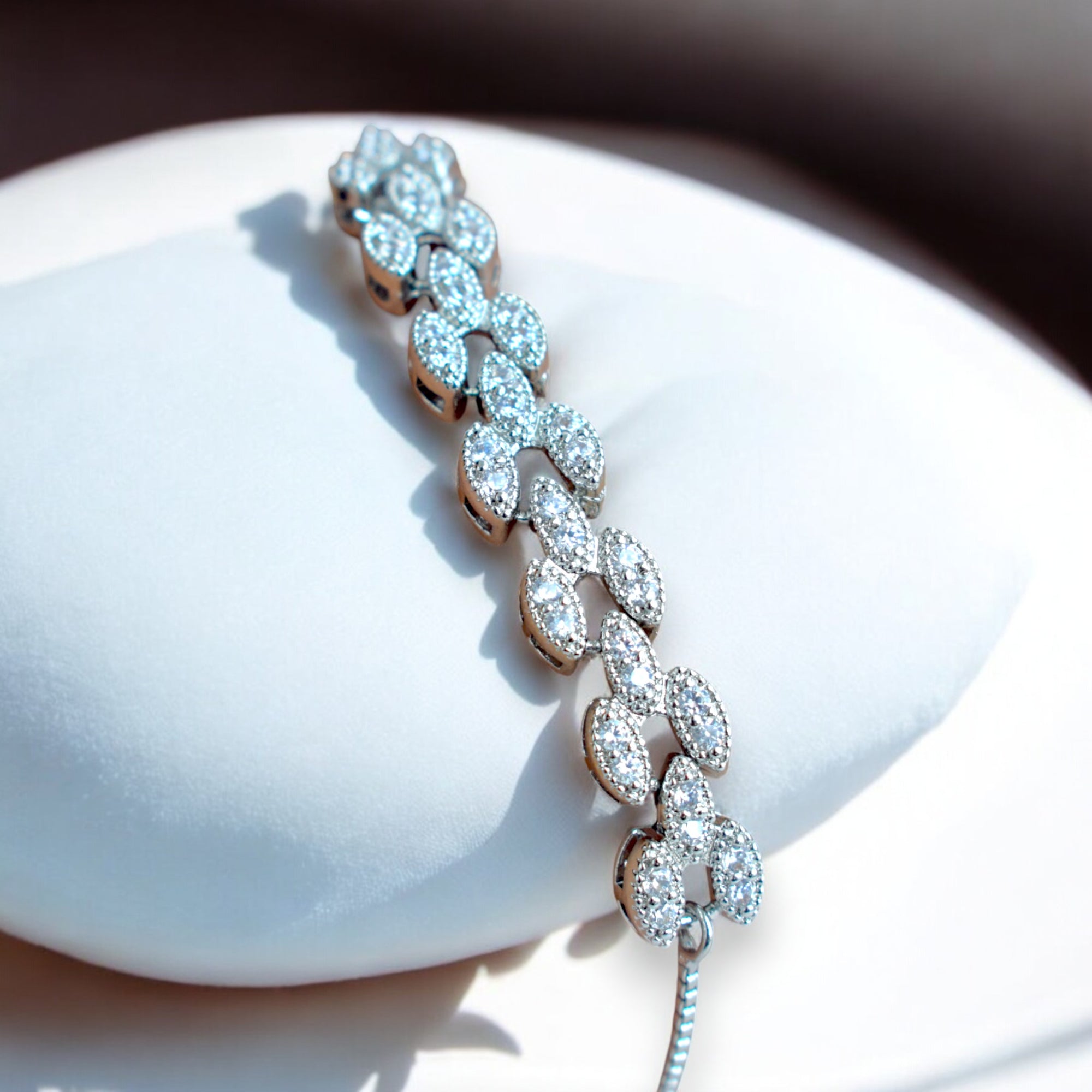 white diamond studded silver bracelet on a white cushion