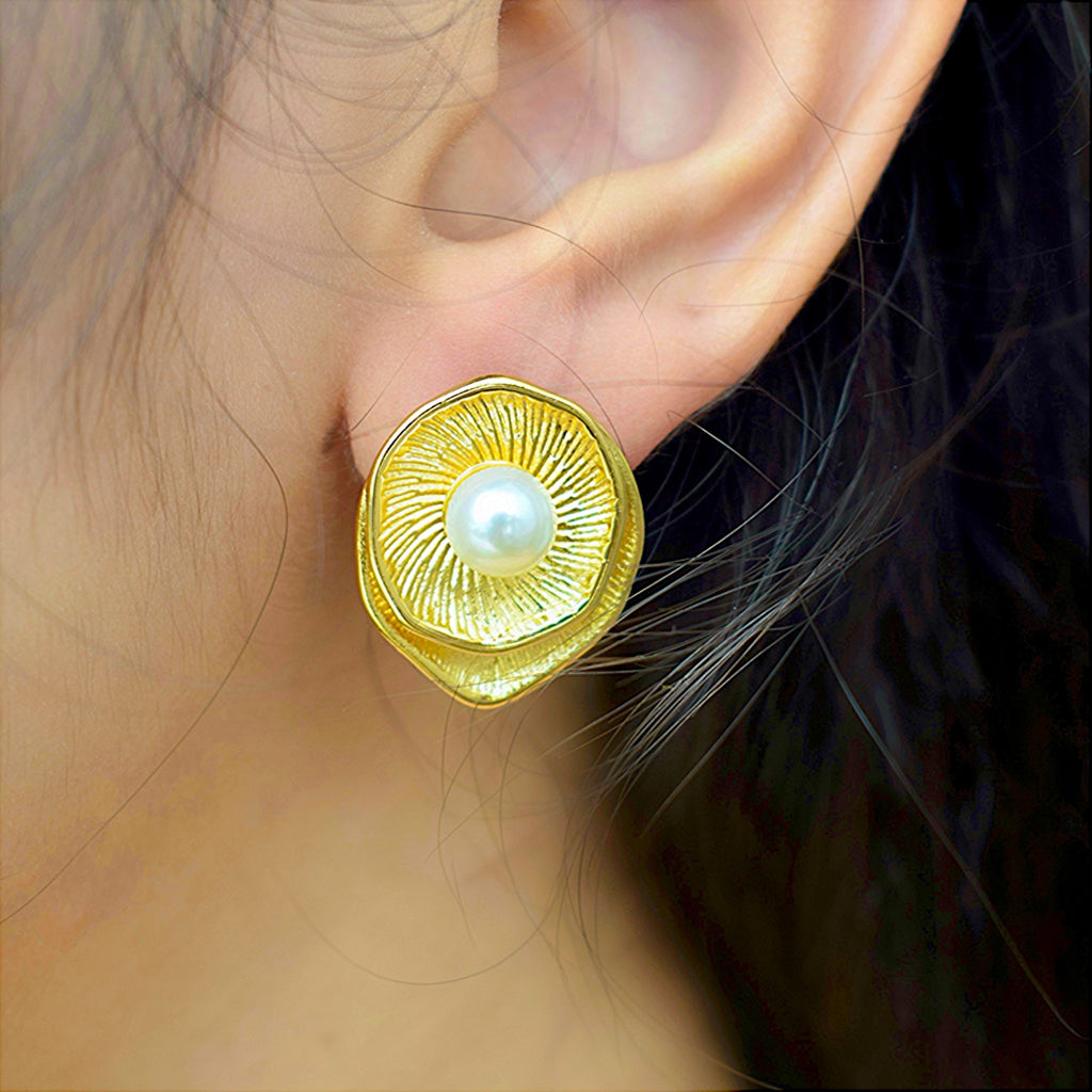 Side view of a girl wearing a golden earrings with a white pearl at the center