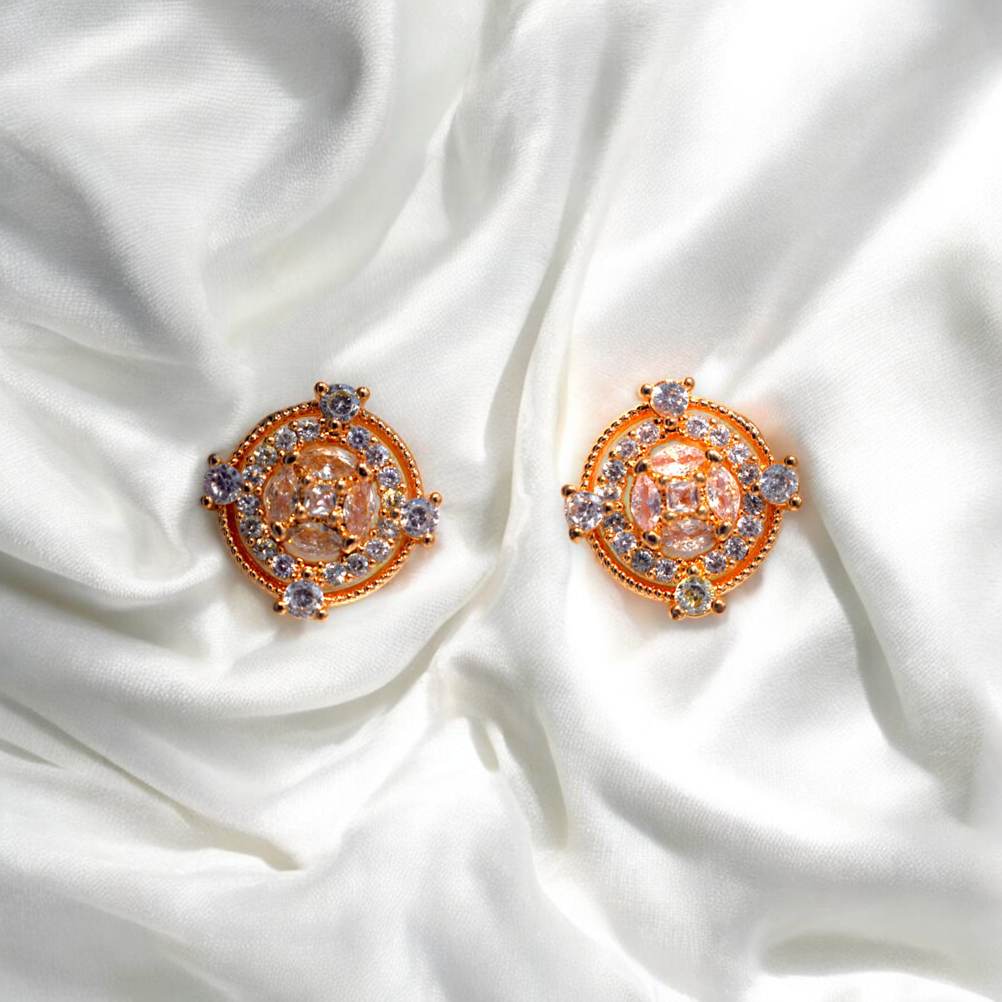 Round Gold zirconia stoned earrings placed on a satin cloth