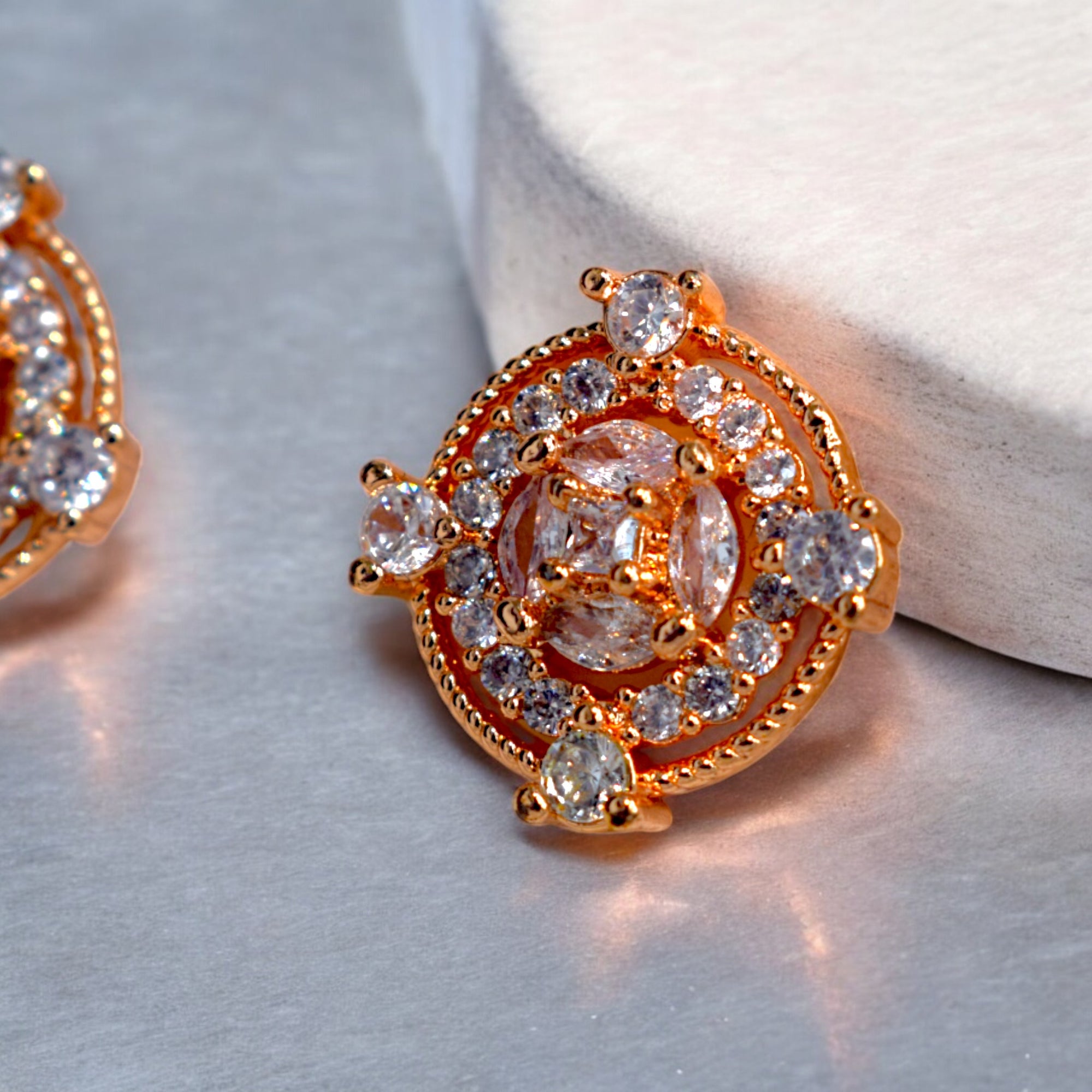Close up of Round Gold zirconia stoned earrings placed on a white marble block