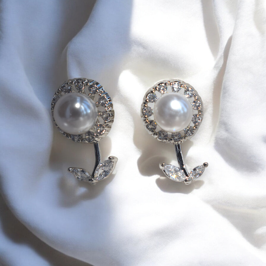 Kansobi Silver Pearl Zirconia Stone earrings kept on a white satin cloth