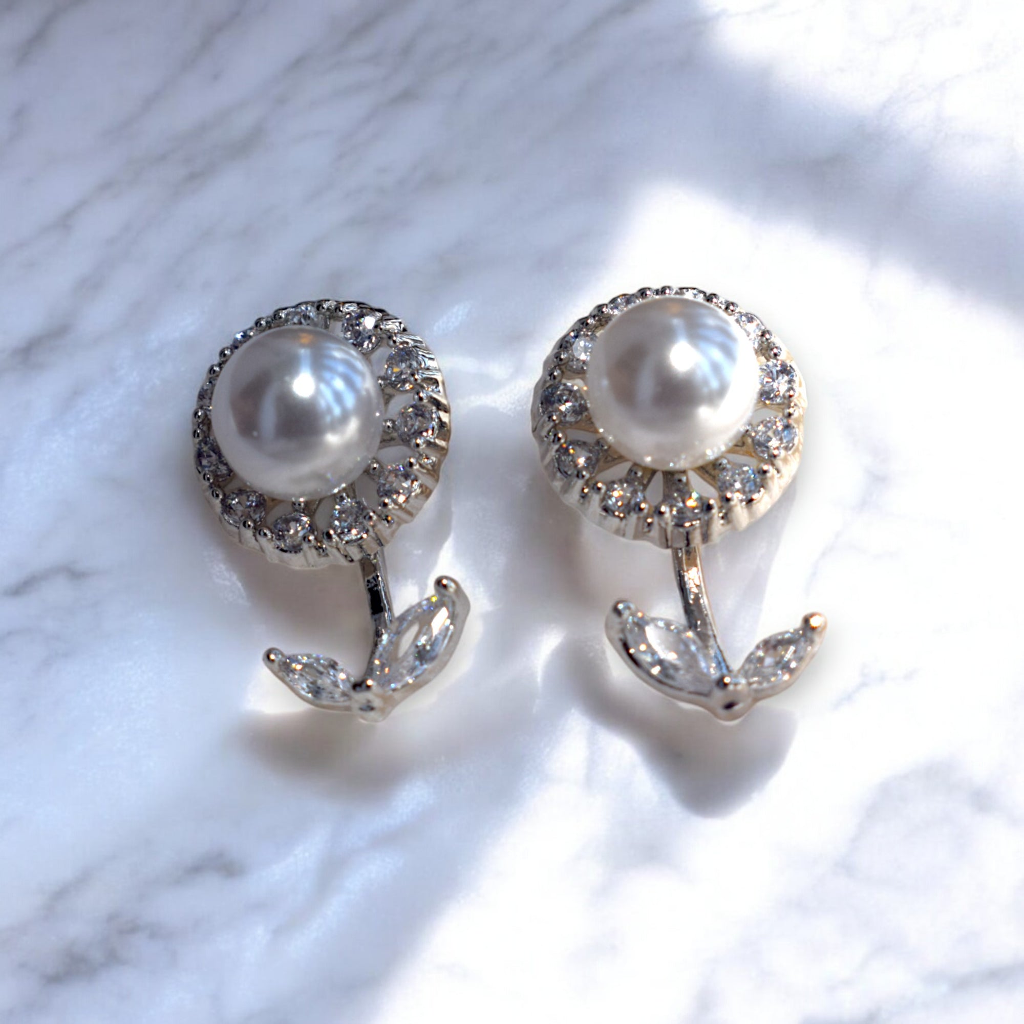 Kansobi Silver Pearl Zirconia Stone earrings kept on a white marble floor