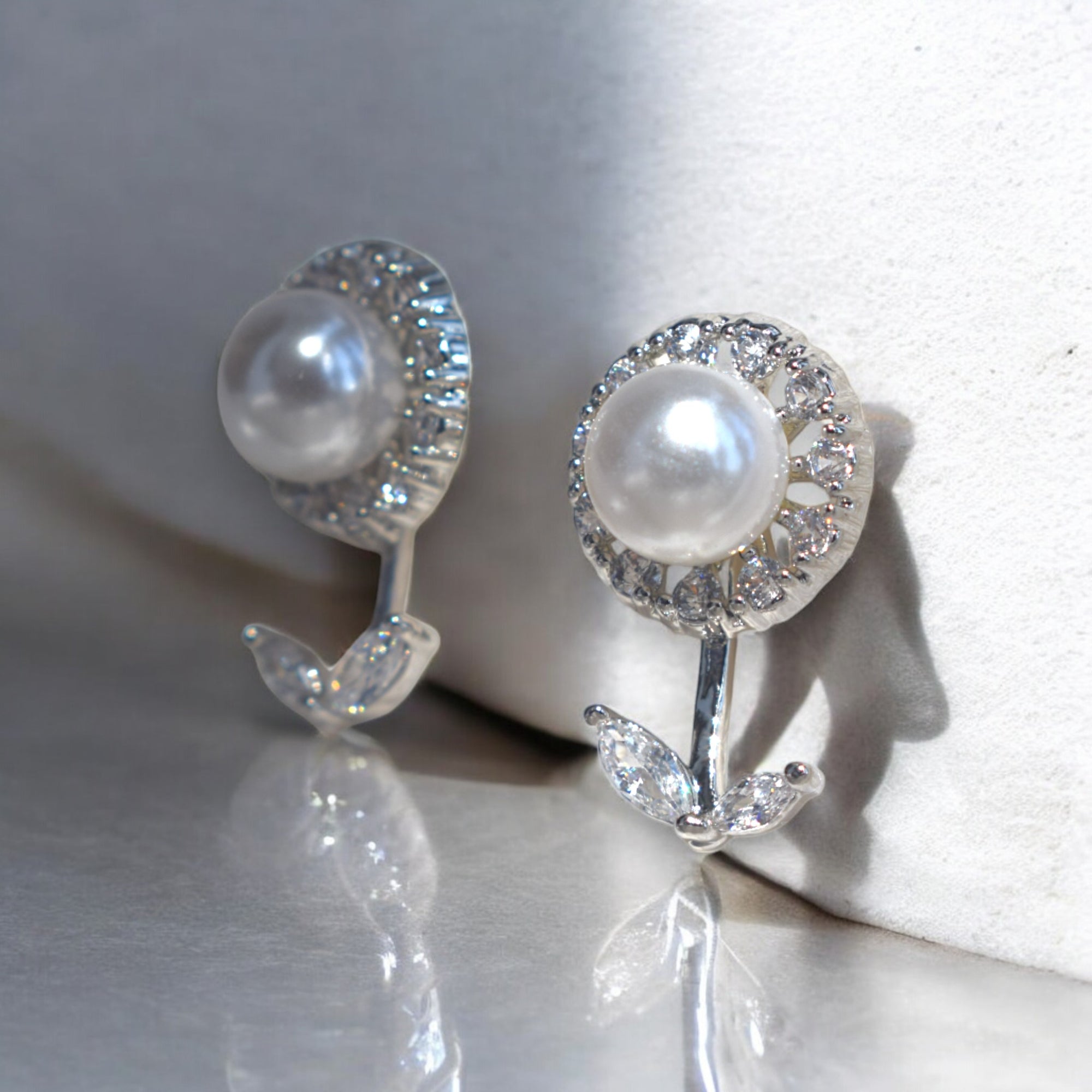 Kansobi Silver Pearl Zirconia Stone earrings kept on a white wall