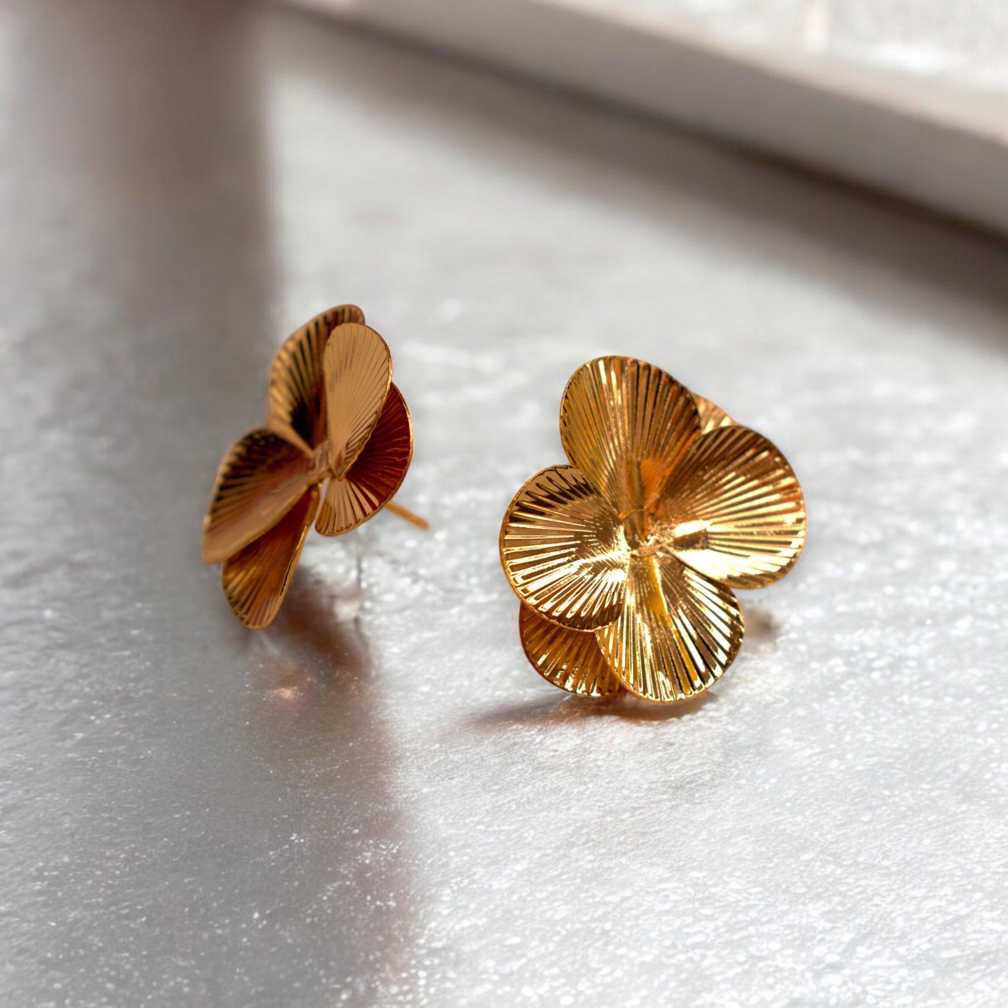 14k Gold flower petal earrings on a white marble floor