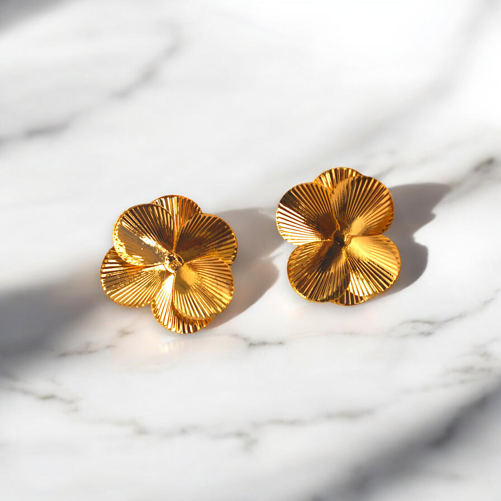 14k Gold flower petal earrings on a white marble countertop 