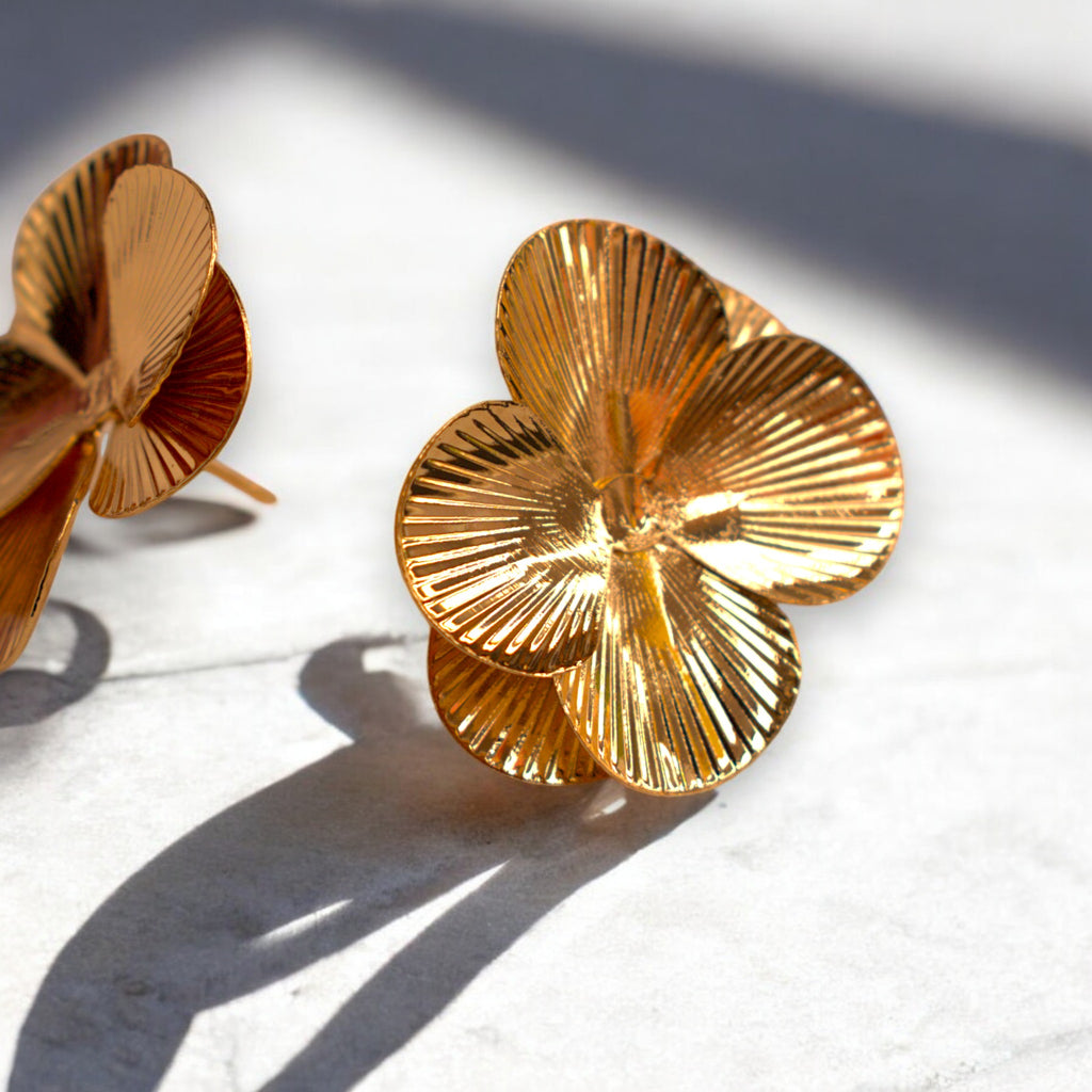 close up of a 14k Gold flower petal earrings on a white marble countertop