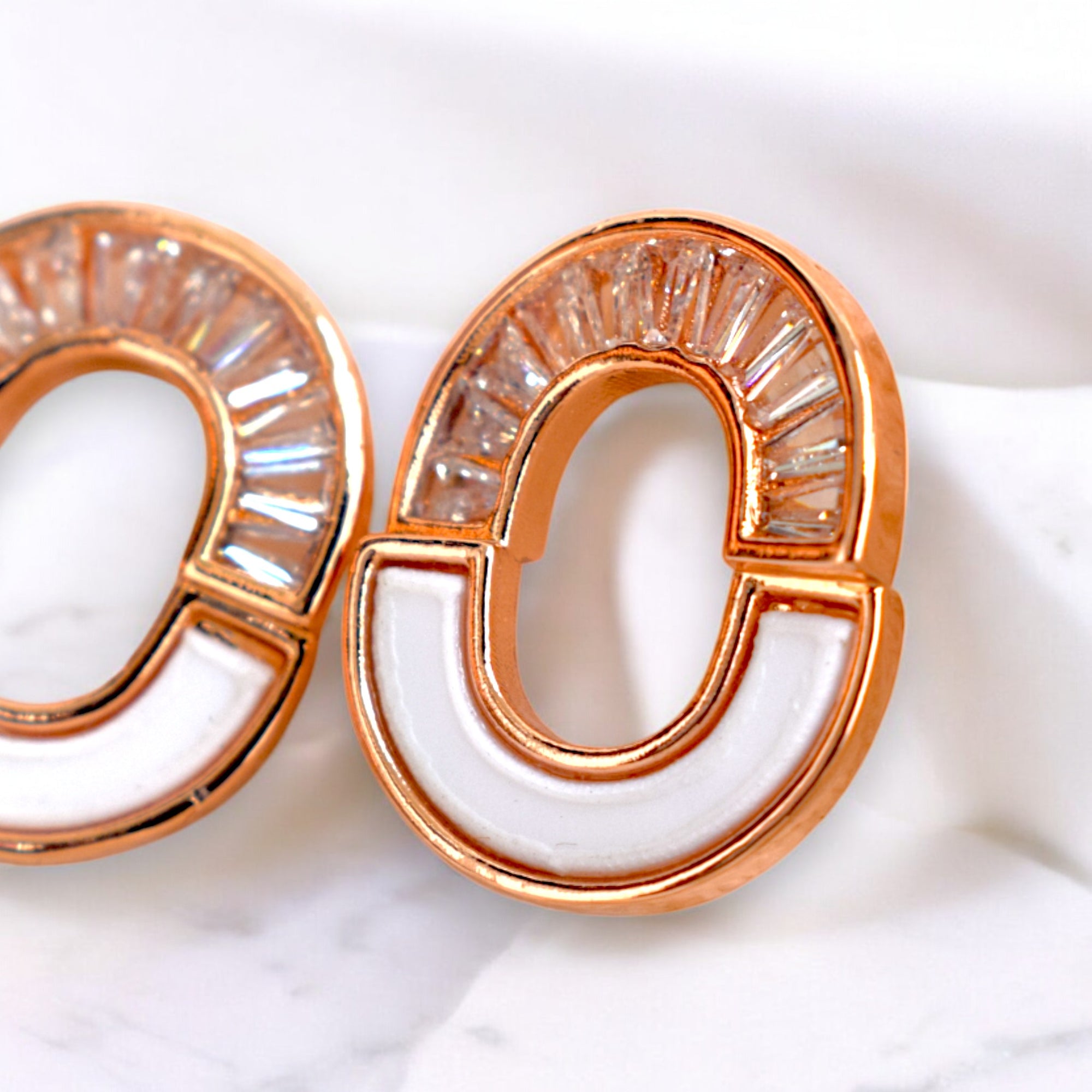 close up of kansobi Rose gold round zirconia stone earrings on a white marble floor