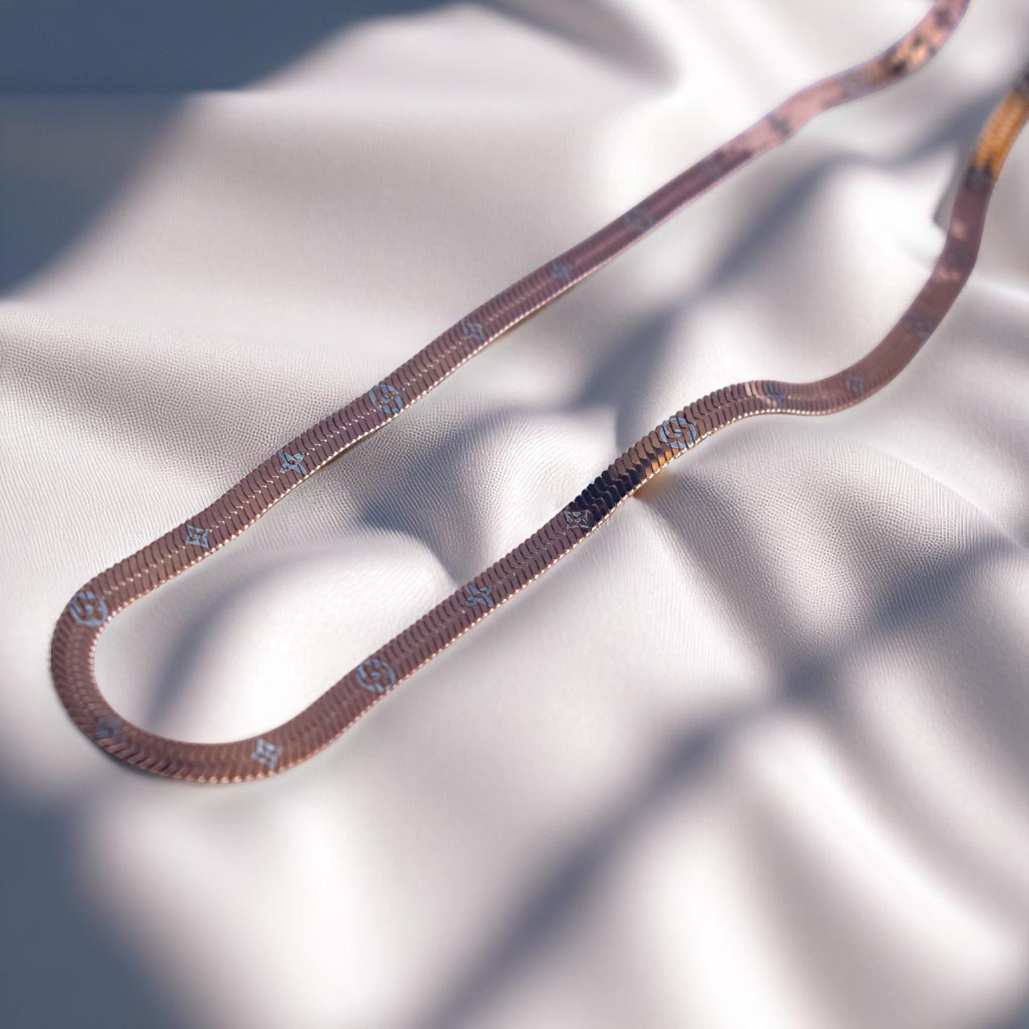 Decorative snake chain with gold and brown pattern on a white background