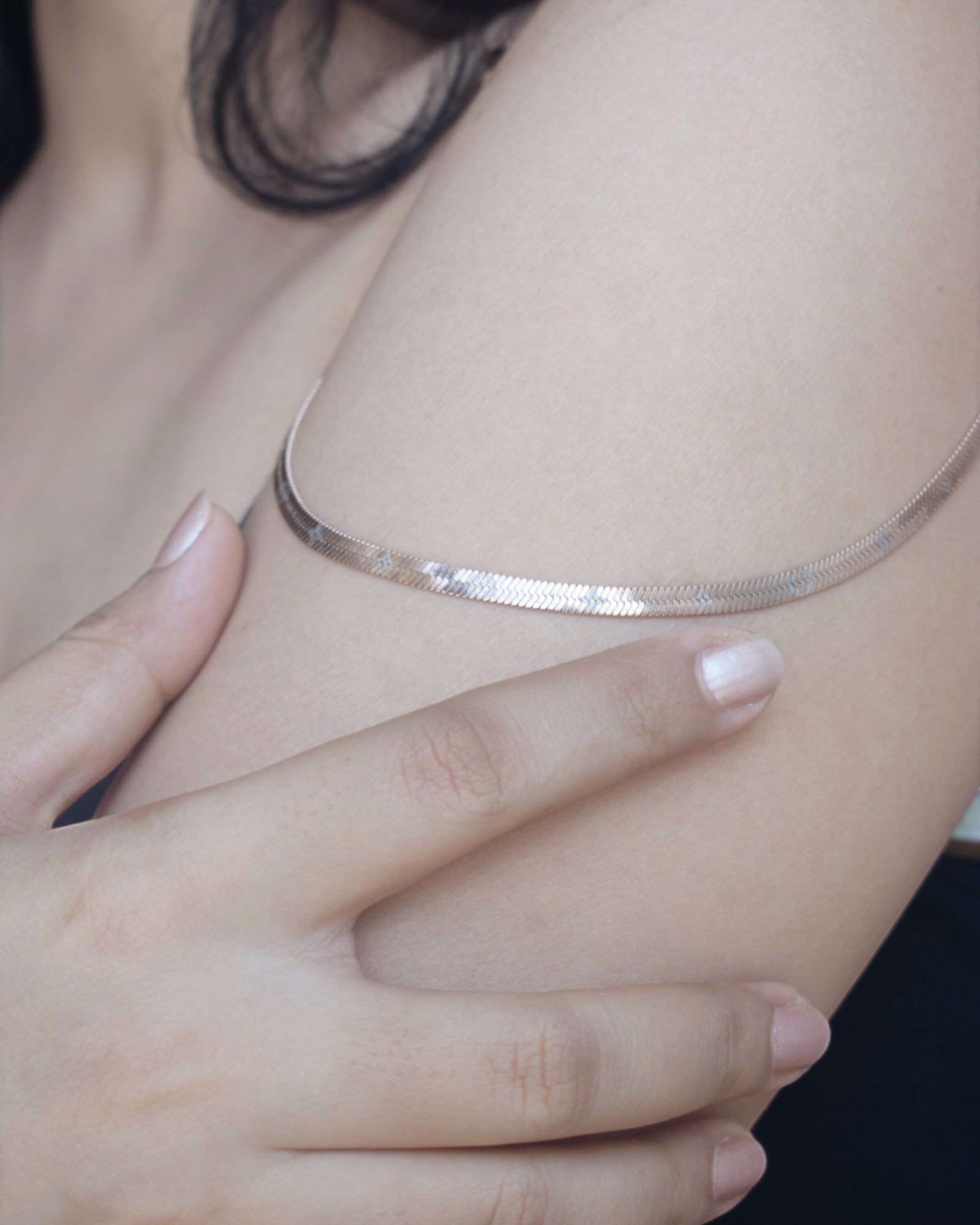 Silver necklace being worn on a person's neck with a blurred background