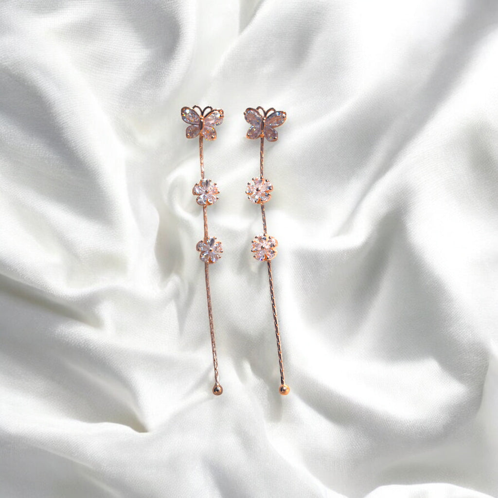 Rose gold butterfly earrings kept on a white satin cloth