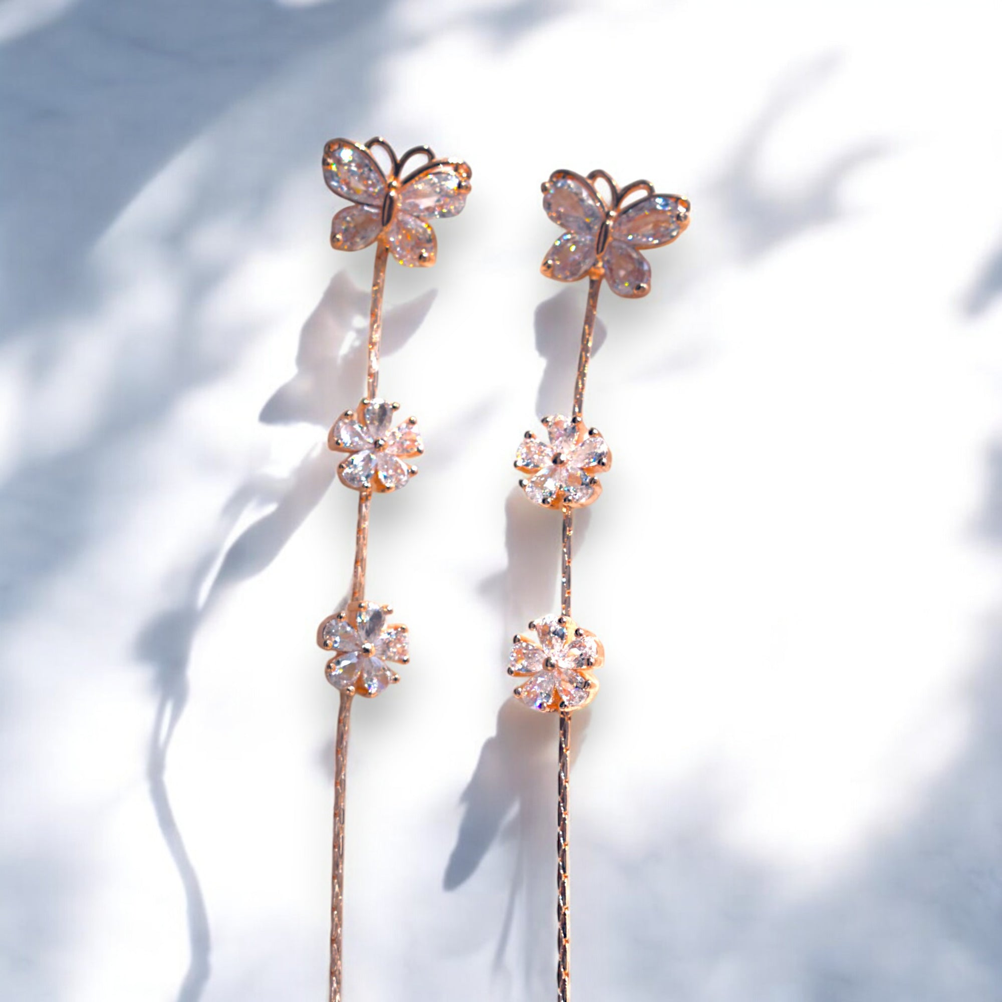 Rose gold butterfly earrings kept on a white marble floor