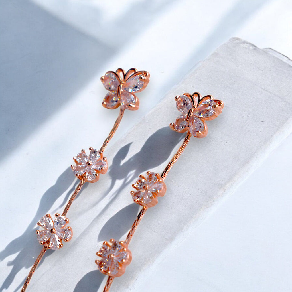 Close up of a Rose gold butterfly earrings kept on a white marble floor