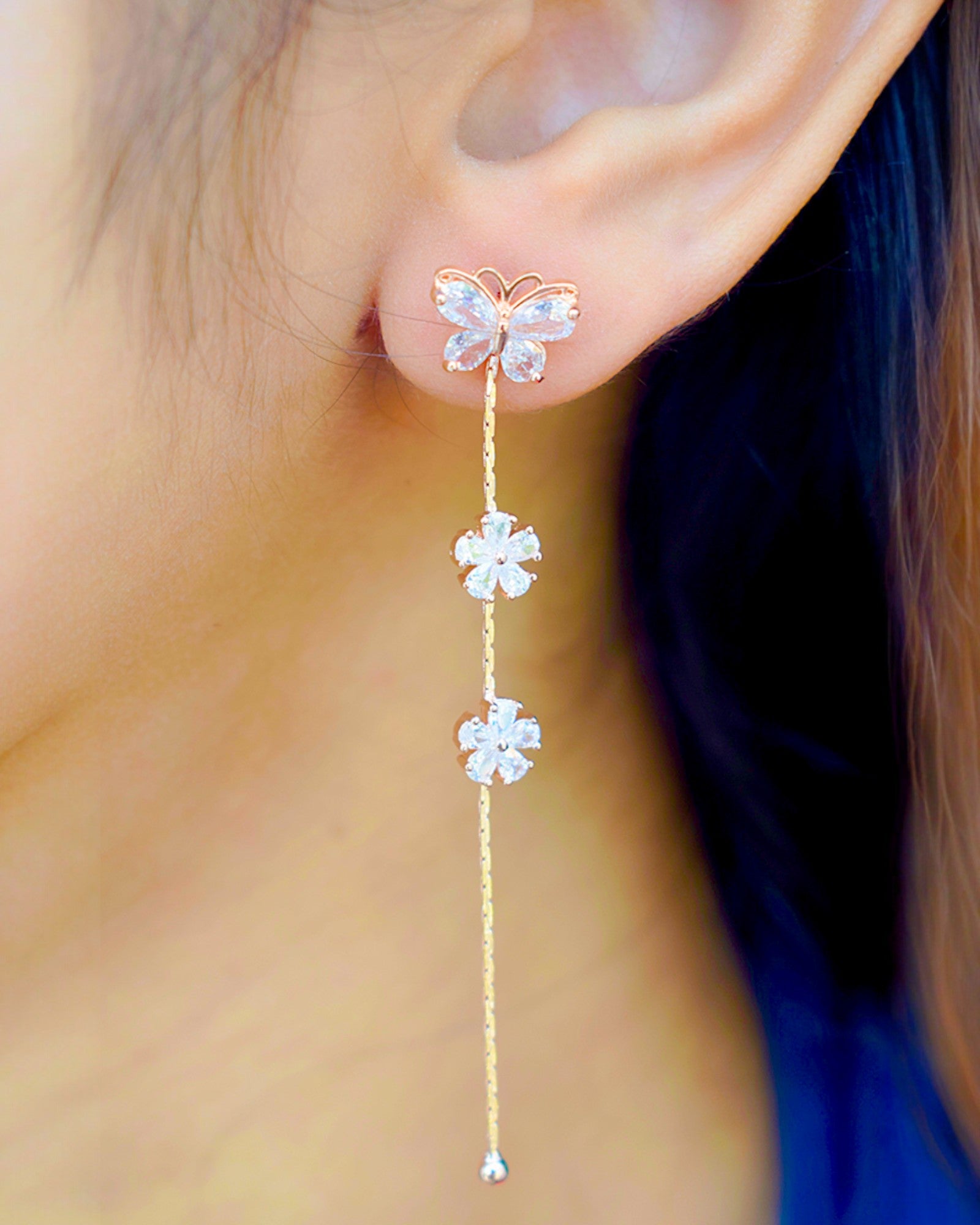 a girl wearing a long rose gold butterfly zirconia stoned earring