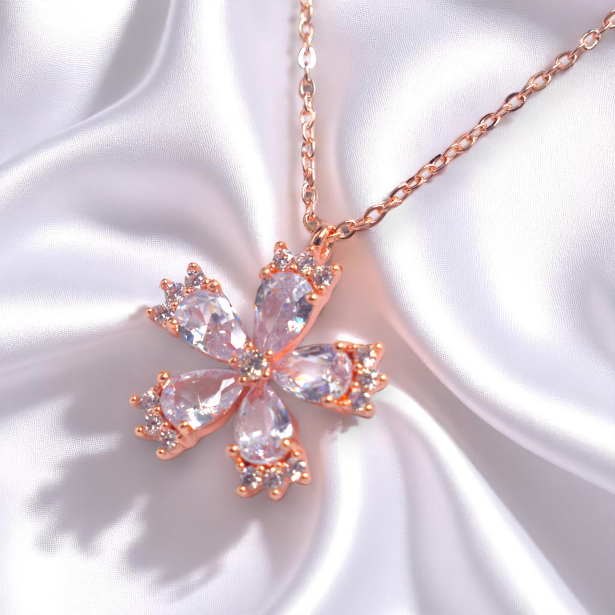 Butterfly-shaped necklace with rose gold accents on a white fabric background