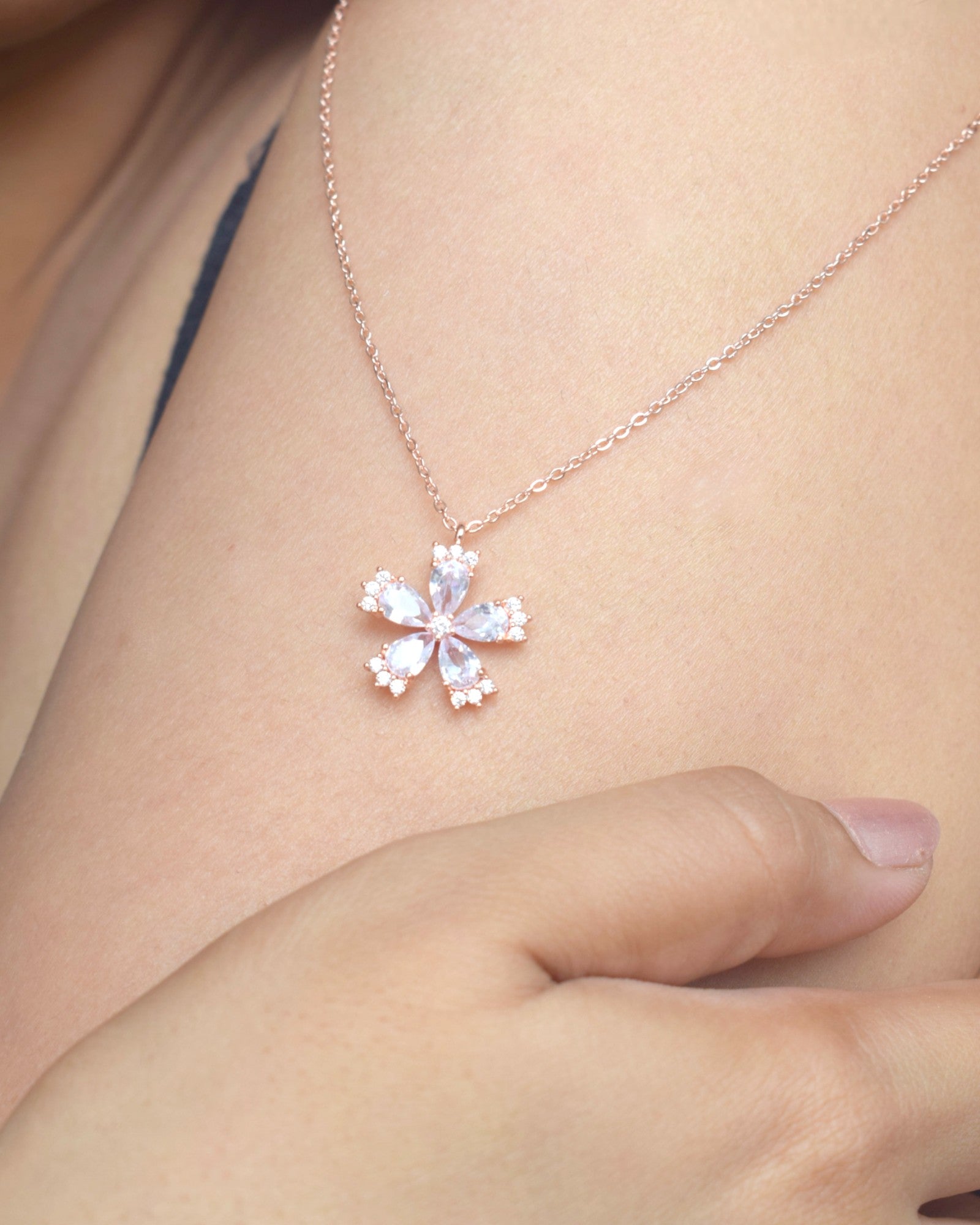 Rose gold necklace with a snowflake pendant on a person's neck