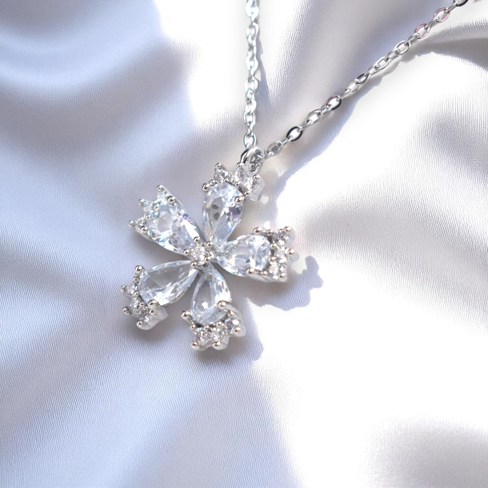 Silver necklace with a bow-shaped pendant on a light fabric background