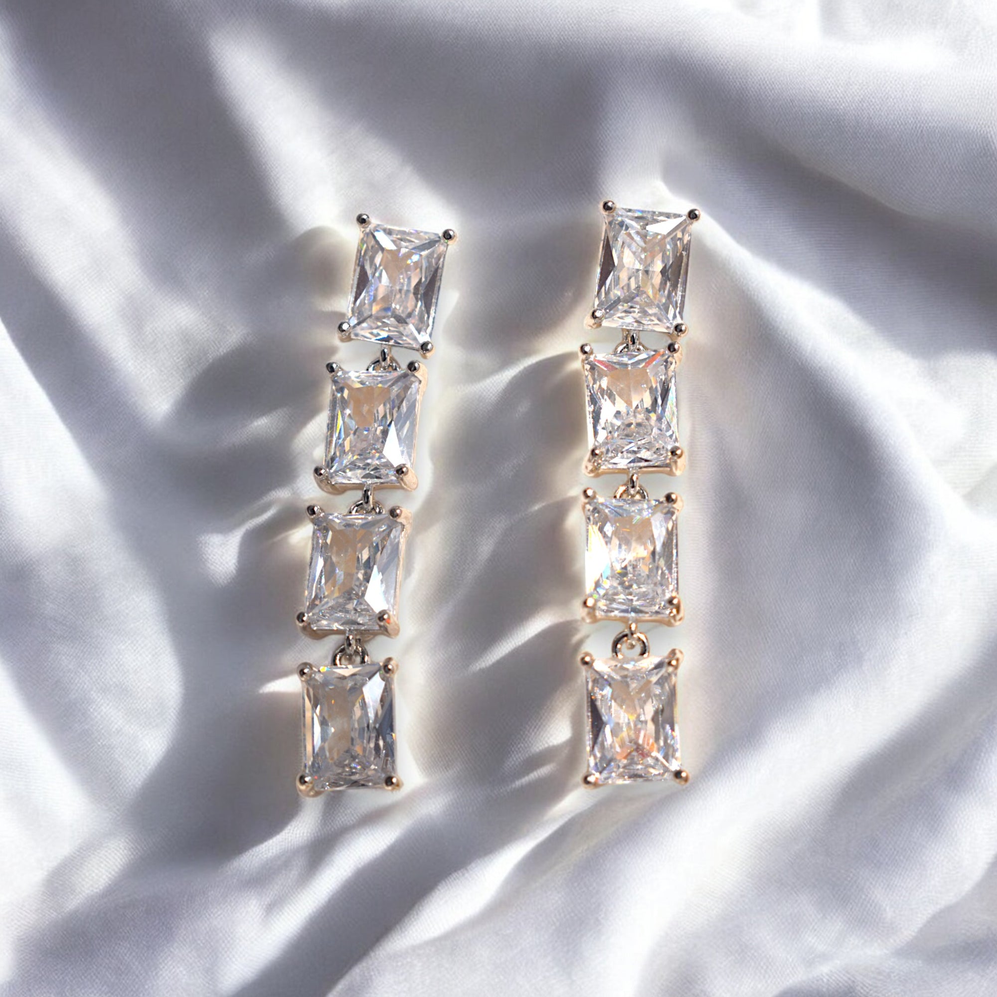 Silver Zirconia square shaped diamond earrings placed on a satin cloth