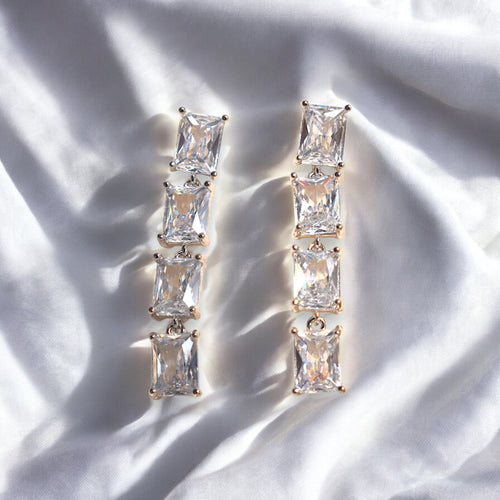 Silver Zirconia square shaped diamond earrings placed on a satin cloth