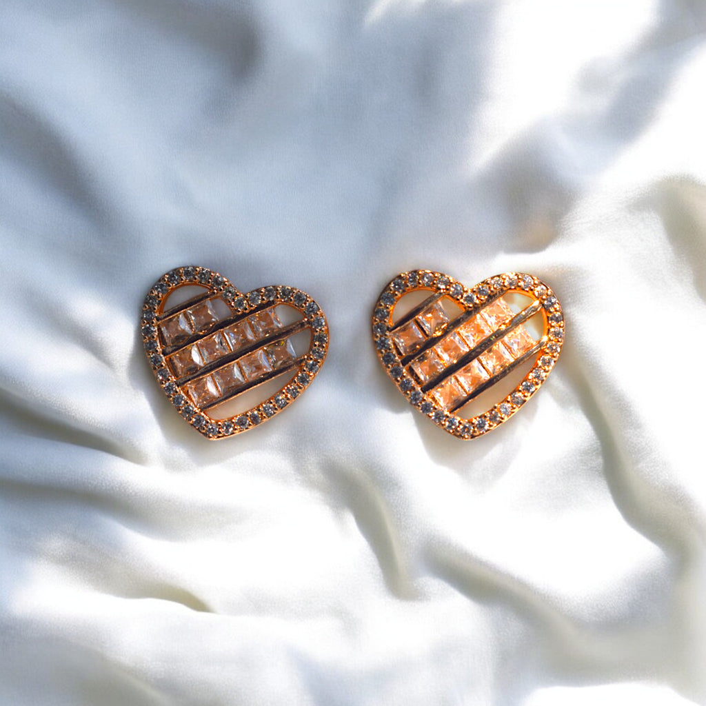 heart shaped zirconia stoned gold earrings placed on a white satin cloth