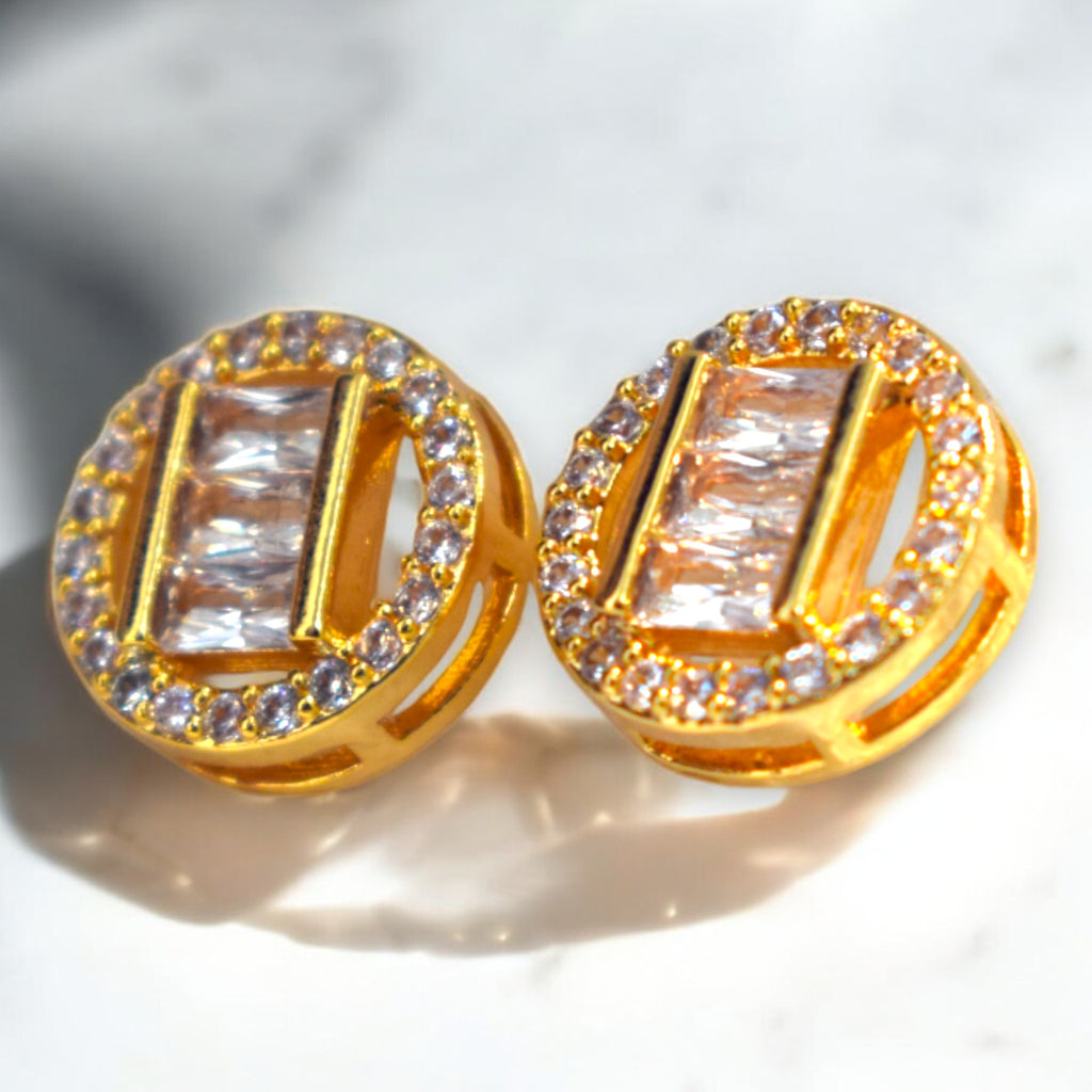 Gold earrings with clear gemstones on a light background
