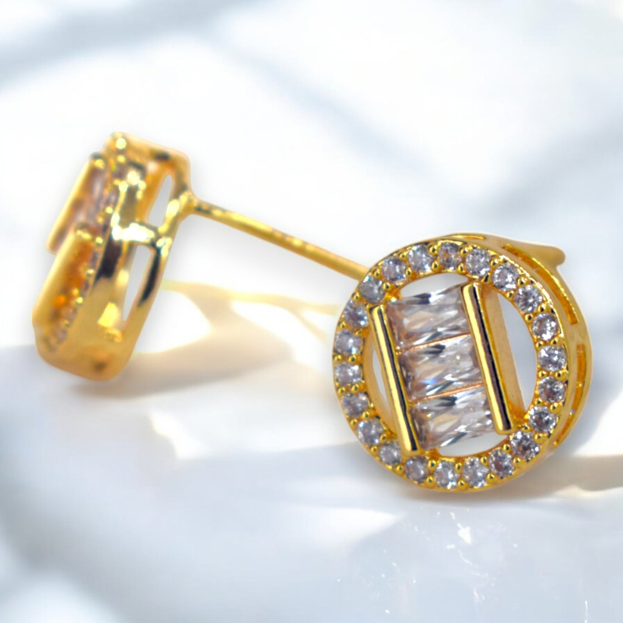 Gold earrings with clear gemstones on a light background