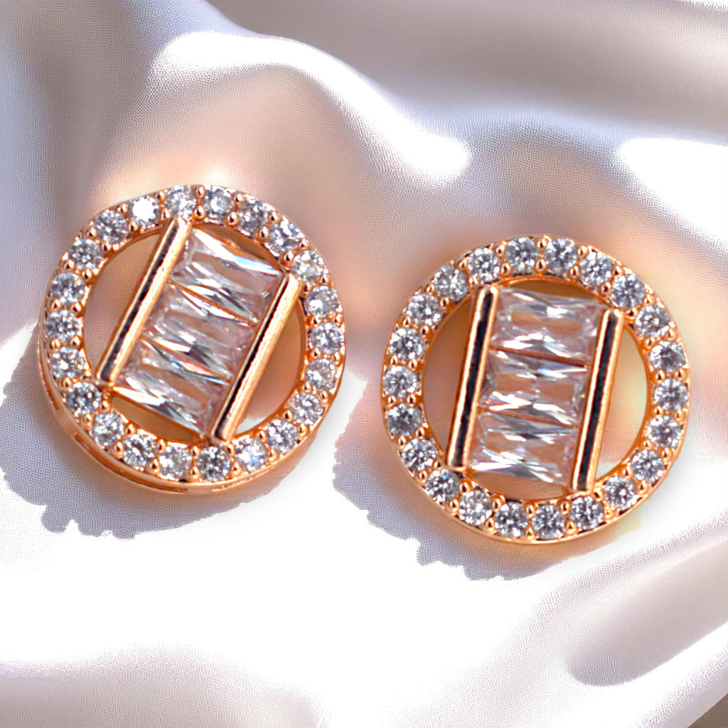 Rose gold earrings with clear gemstones on a white fabric background