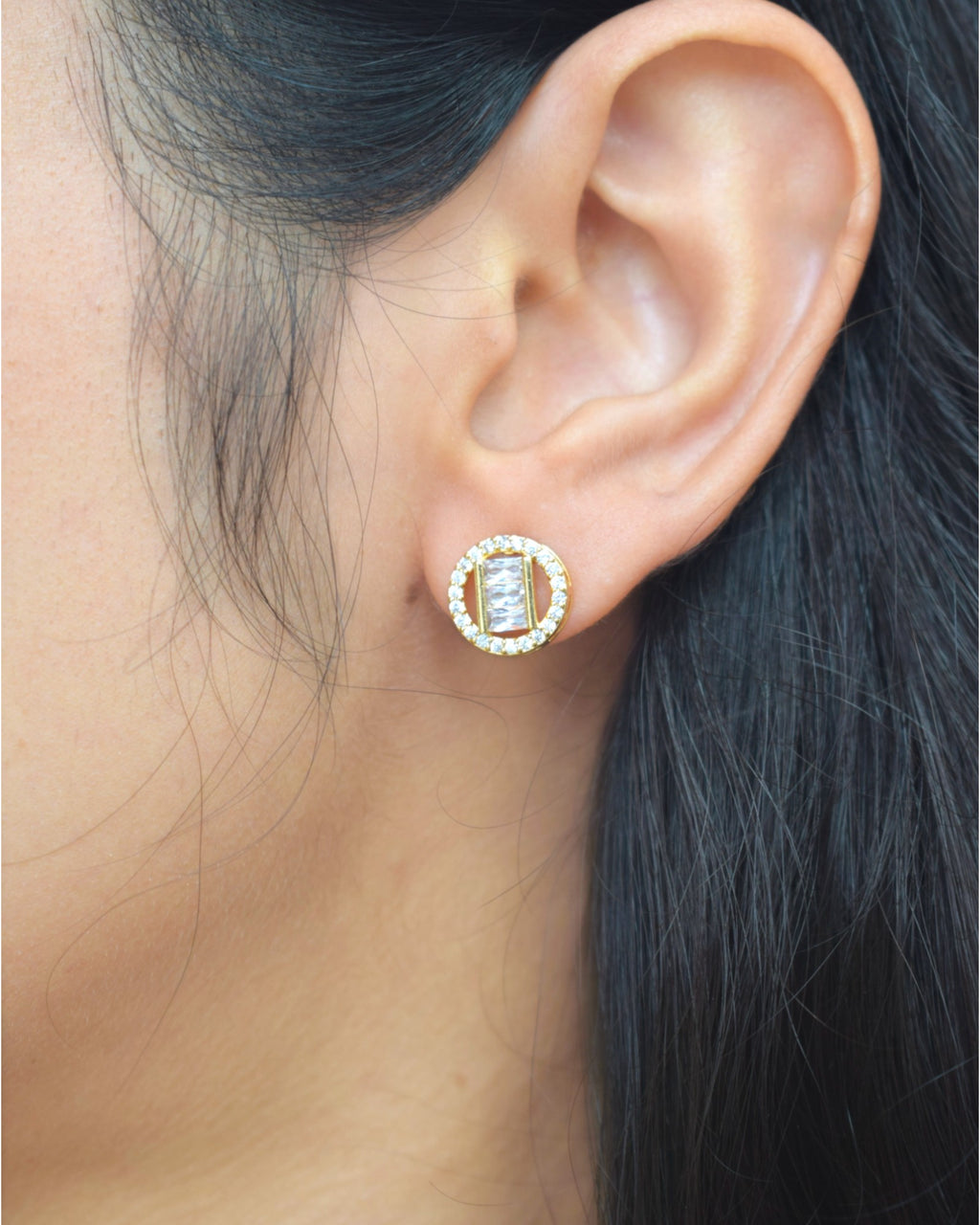 Close-up of an ear wearing a diamond stud earring with a blurred background