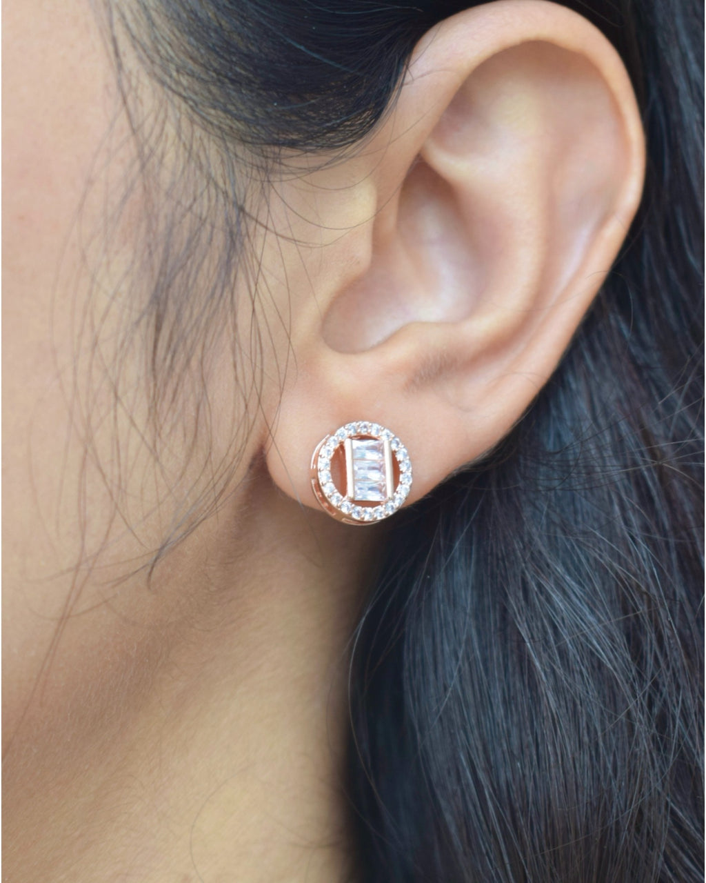 Close-up of an ear wearing a diamond earring with a dark background