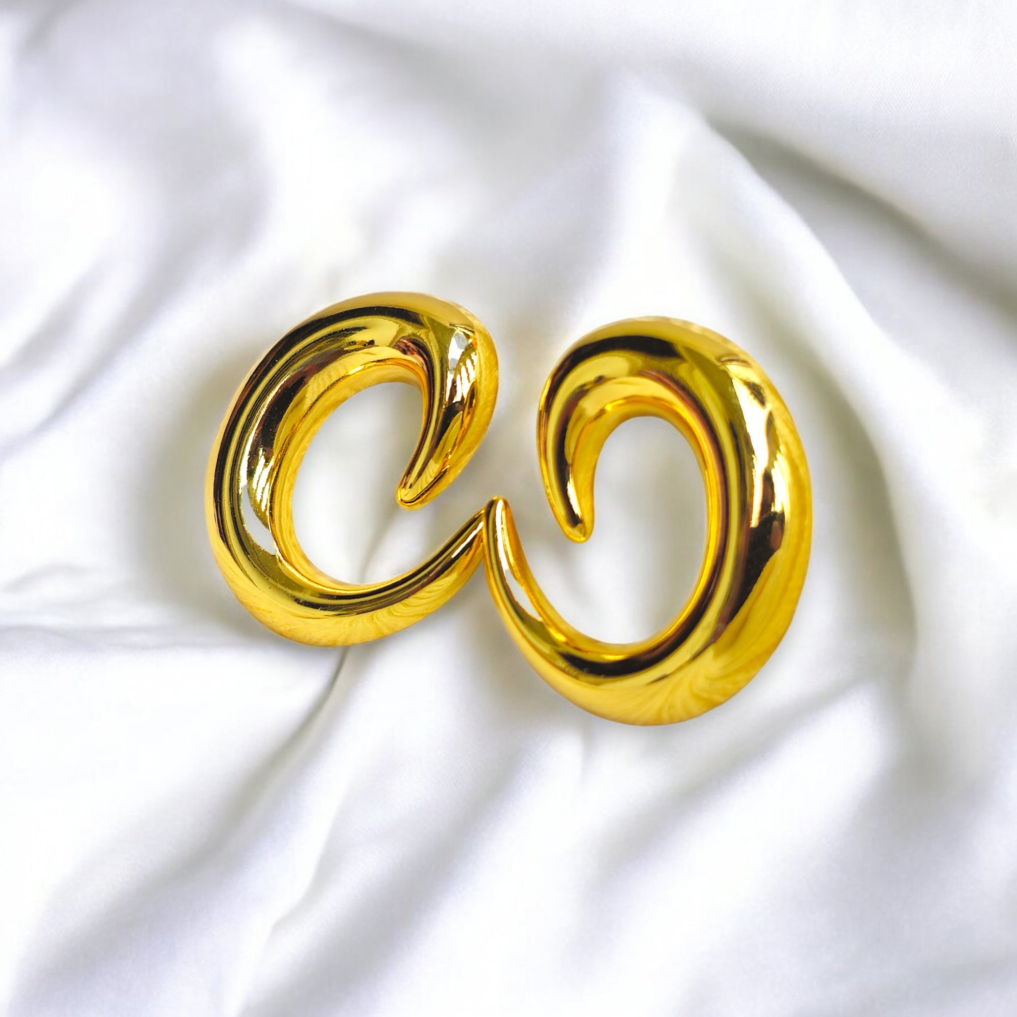 Gold crescent hoop earrings with a bold, high-polish finish, perfect for statement jewelry lovers