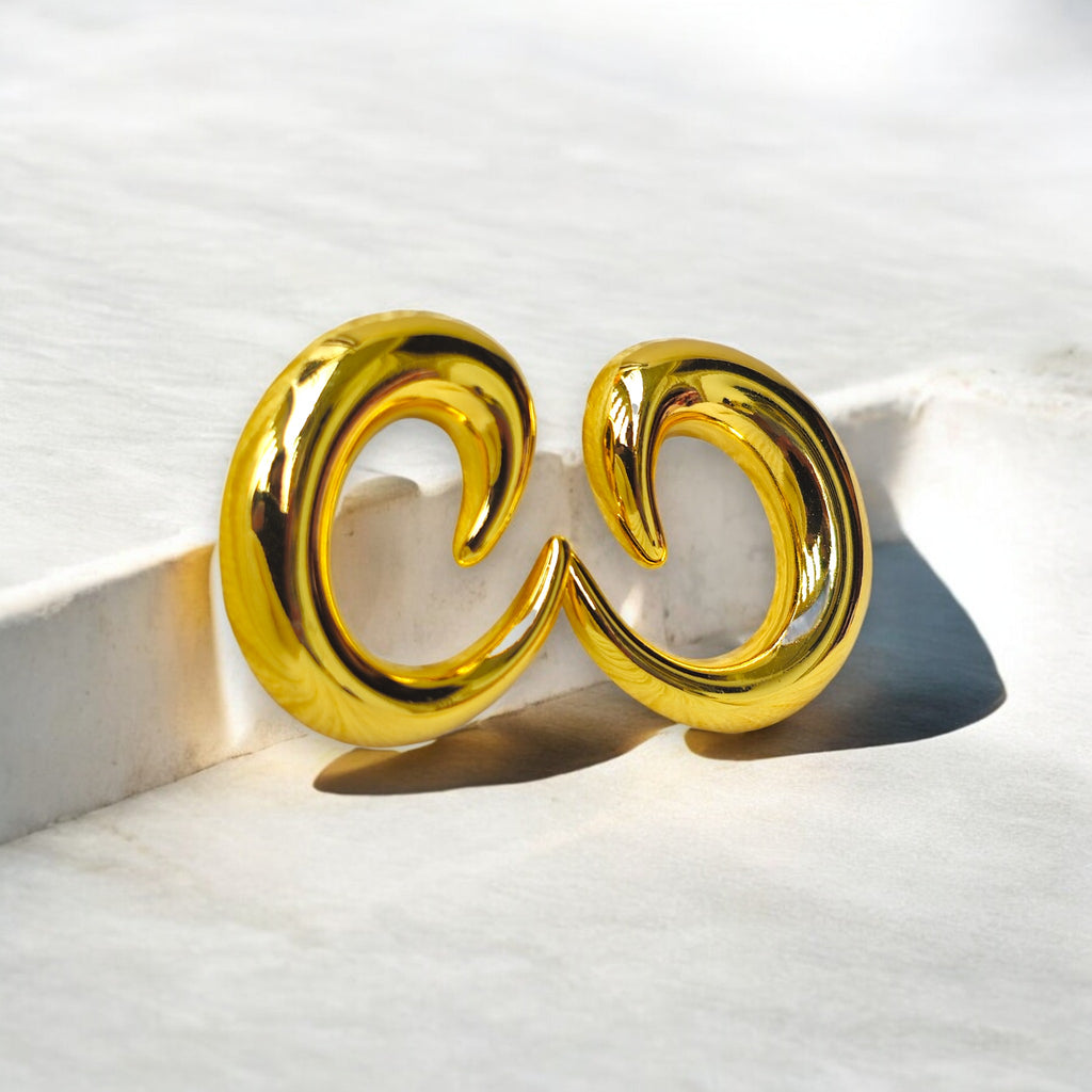 Gold crescent hoop earrings with a bold, high-polish finish, perfect for statement jewelry lovers