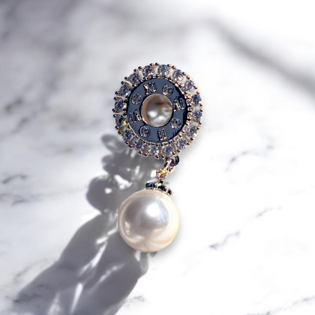 A single zirconia stone studded silver pearl drop earring on a white marble countertop