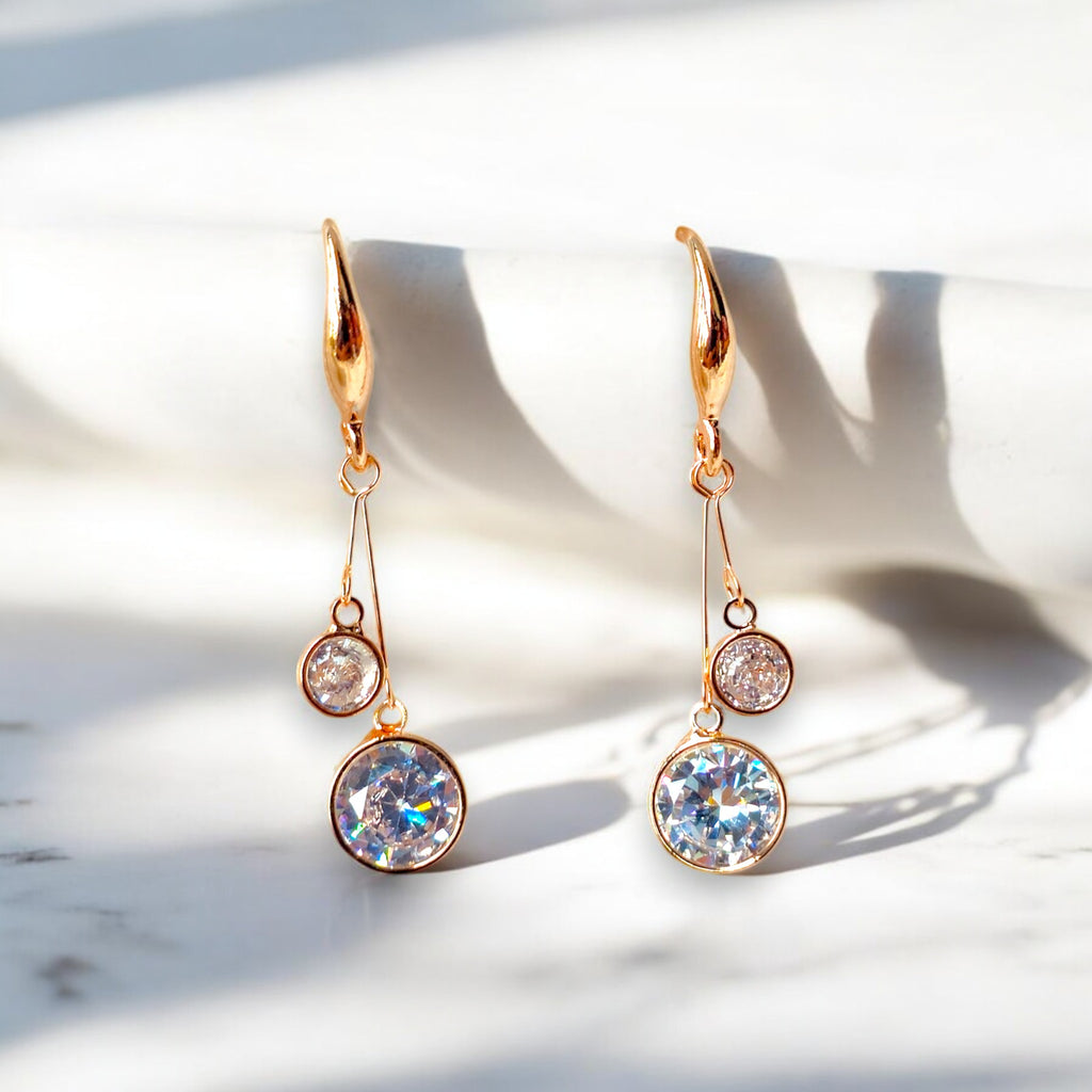 kansobi rose gold drop earrings with round zirconia diamonds placed on a white marble floor