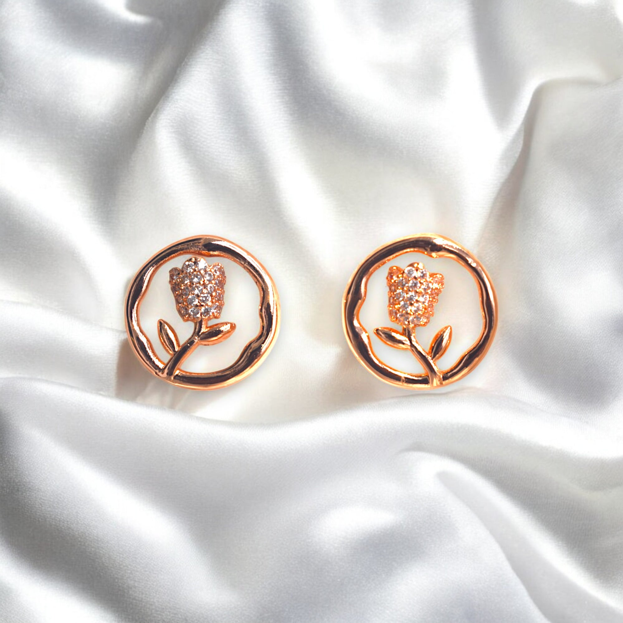 Rose gold round flower earrings with Zirconia stones placed on a satin 