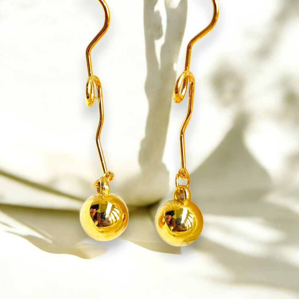Gold plated dangle earrings with a minimalist orb design in a  white background