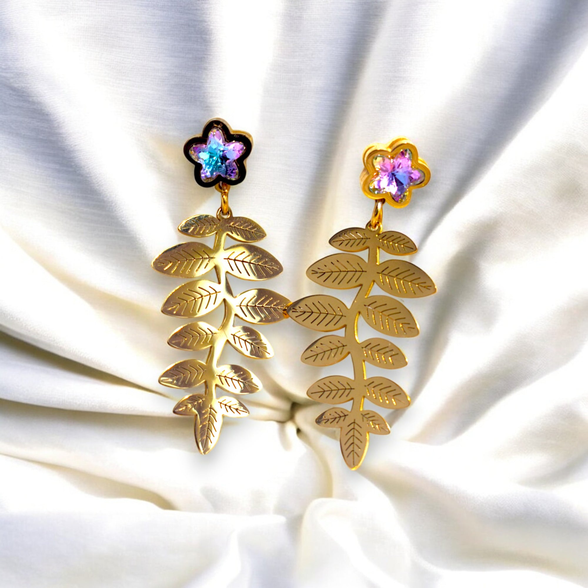 14k golden fern leaf earring with zirconia star diamonds on a white satin cloth