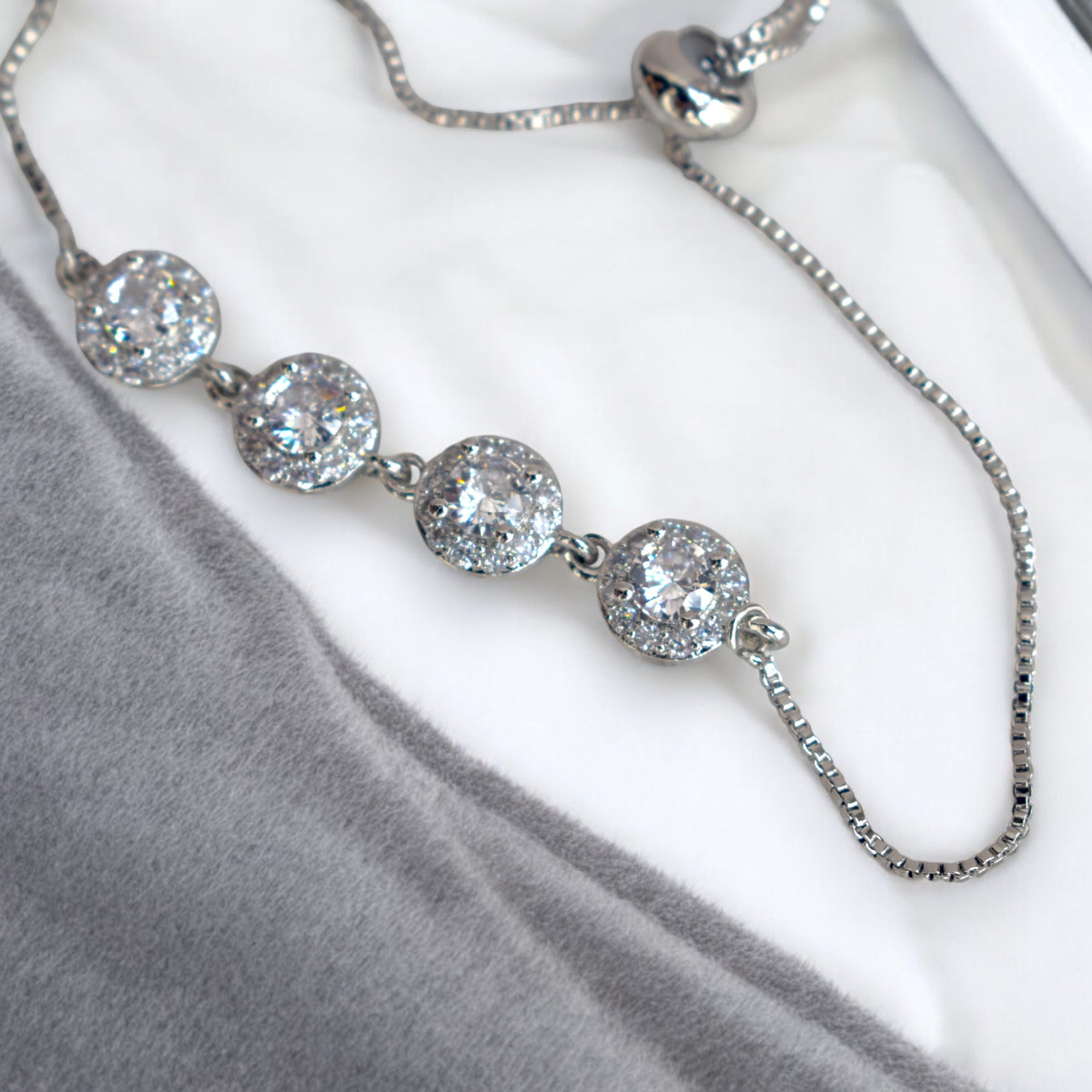 close up of a diamond stoned silver circle chain bracelet on a white marble floor