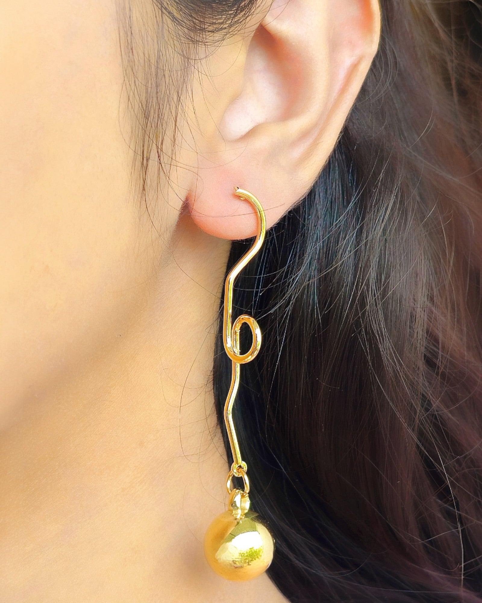 side view of a girl wearing 14k gold polished dangle earrings
