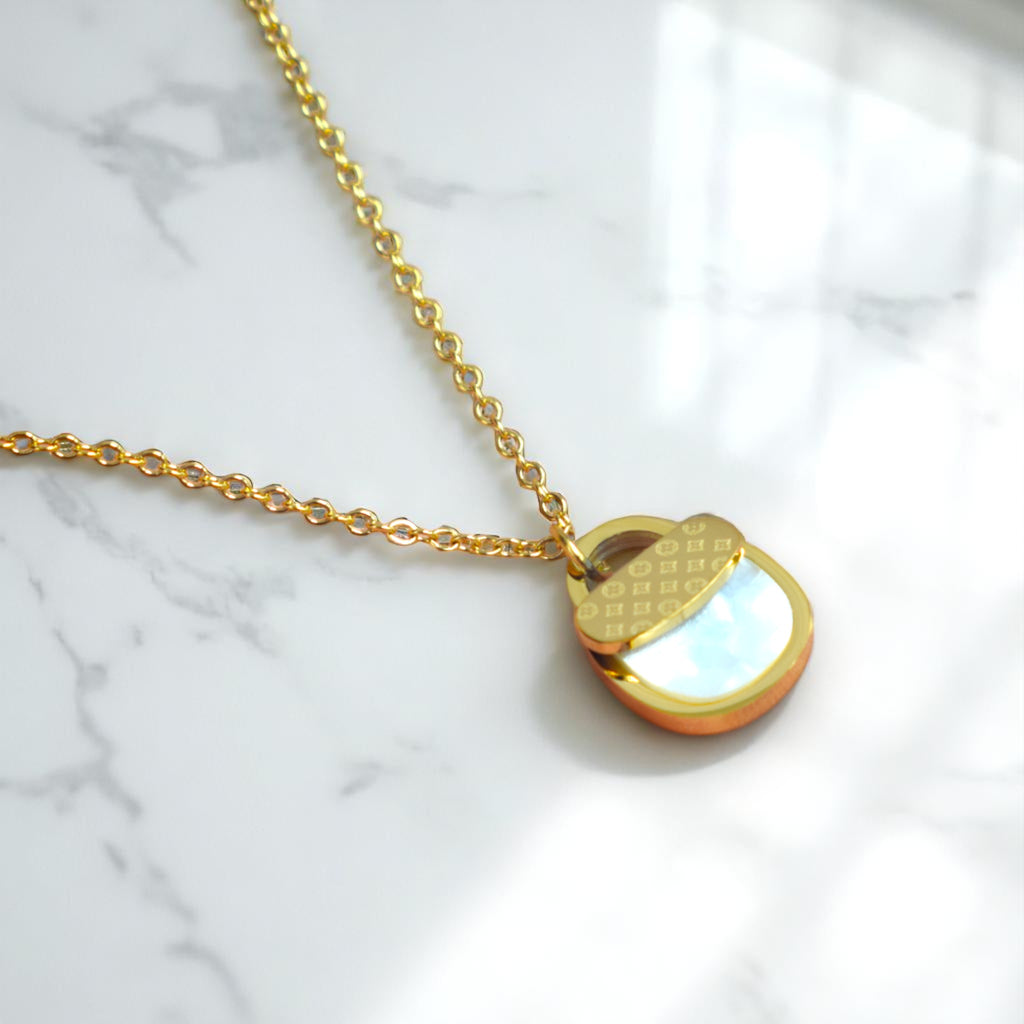 Gold necklace with a heart-shaped pendant on a marble background