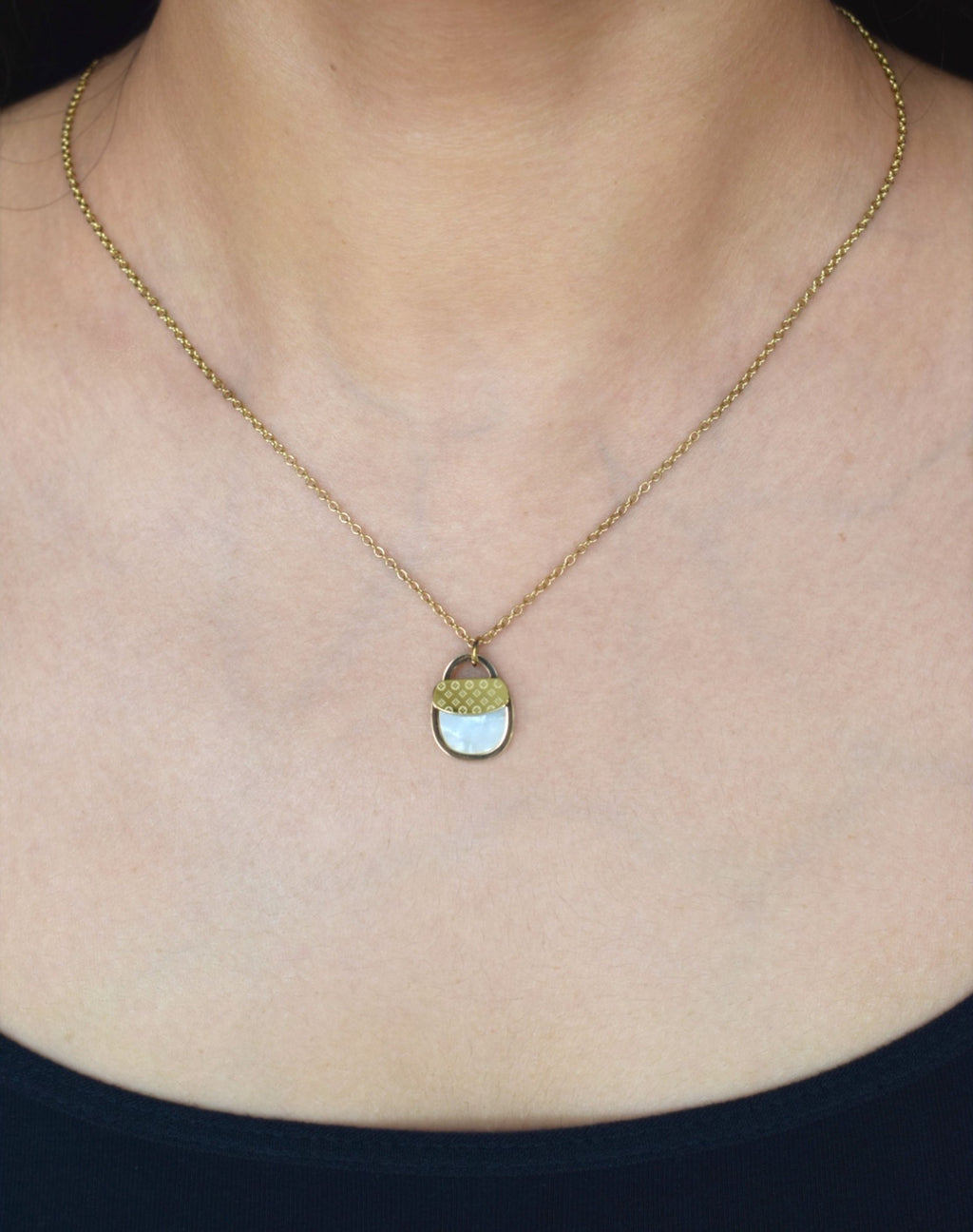 Necklace with a pendant worn by a person against a plain background